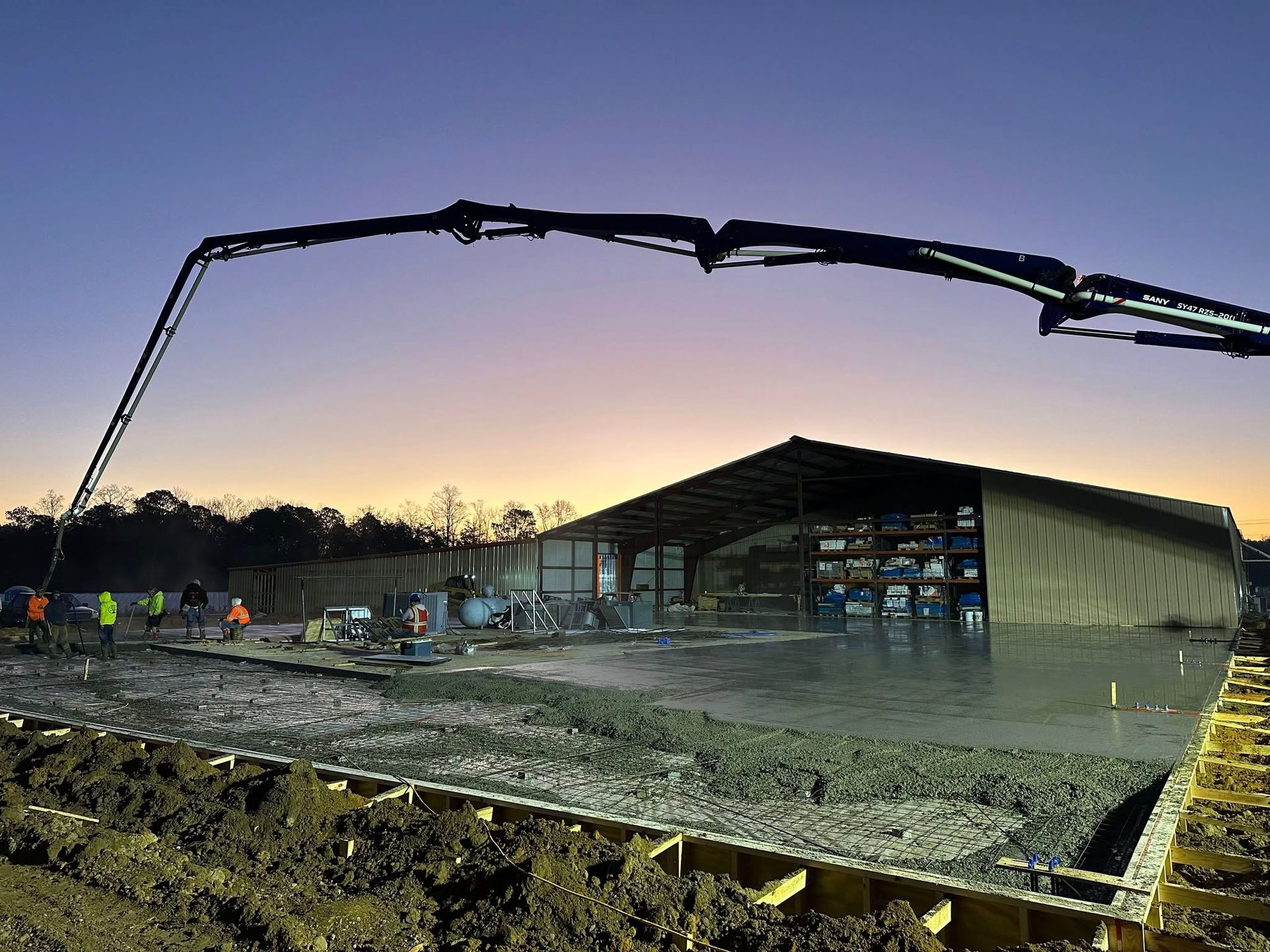 A concrete pump is being used to pour concrete in front of a building under construction.