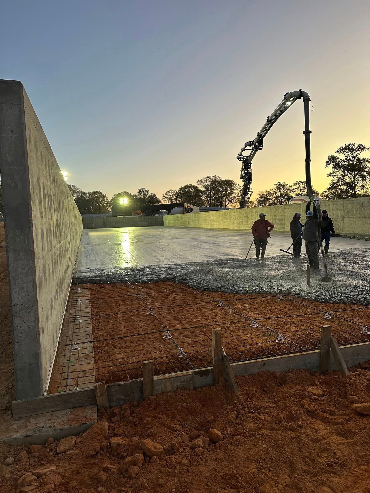A group of people are working on a construction site with a crane pumping concrete.