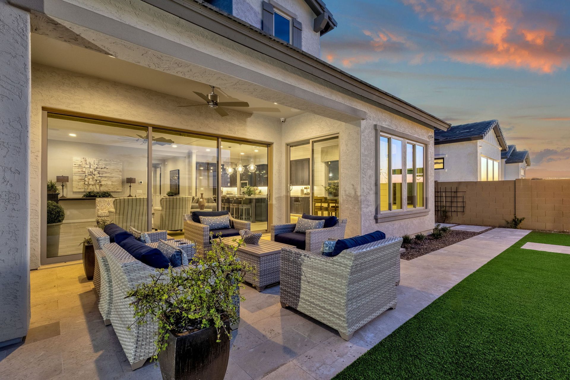 The backyard of a house with a patio area with furniture and a sliding glass door.