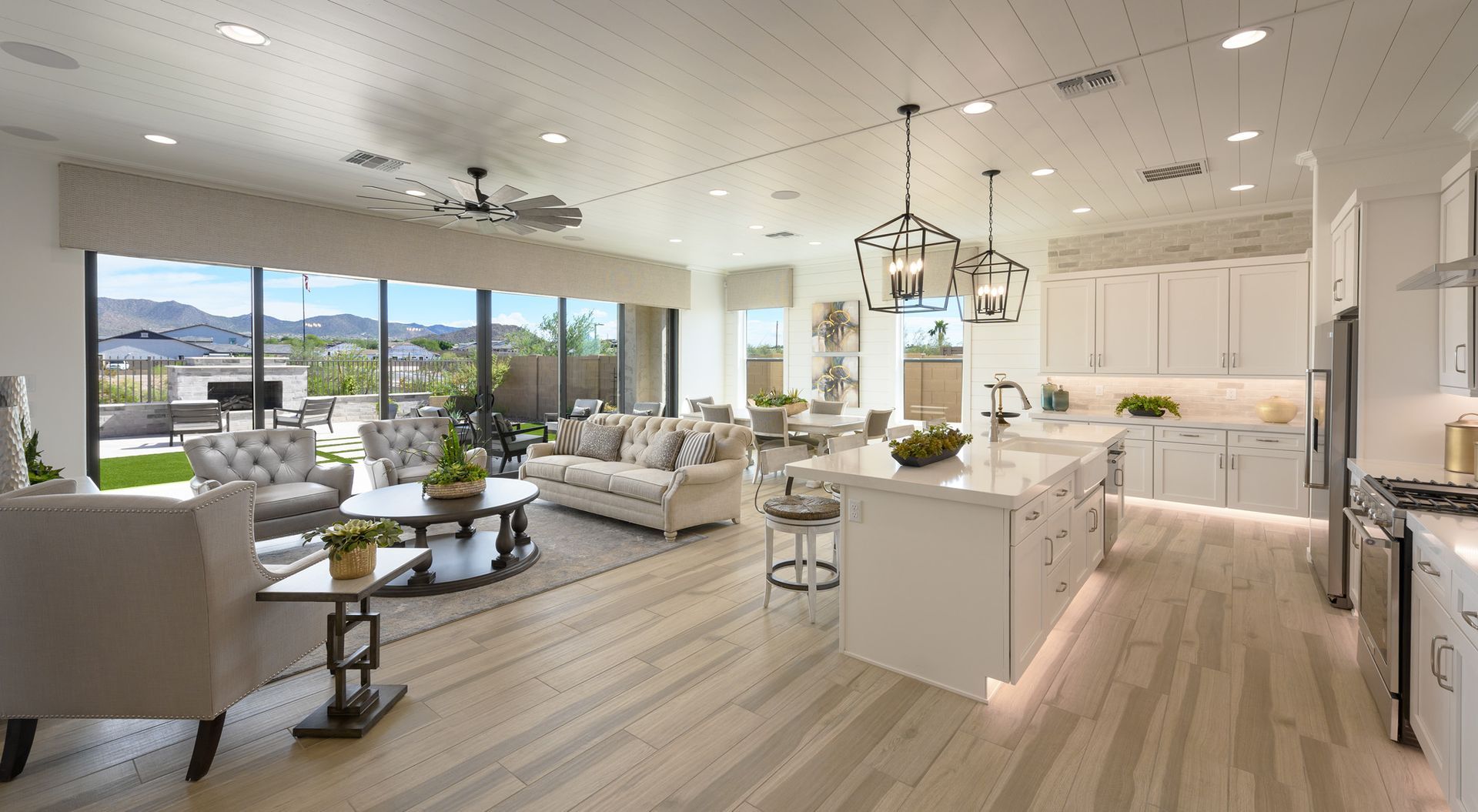 A living room and kitchen in a house with a lot of windows.