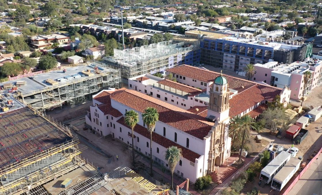 An aerial view of a large building with a clock tower in the middle of a city.