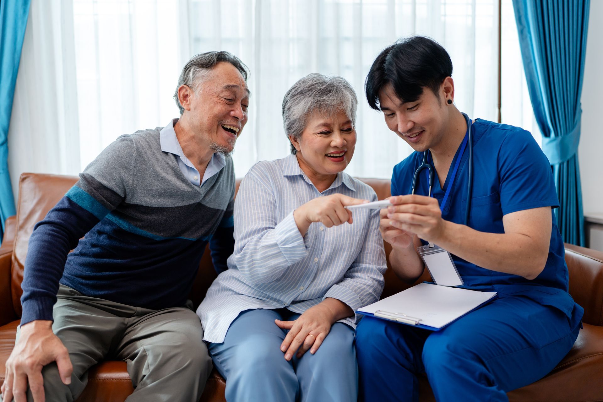A healthcare worker shows a couple a medical test result while they sit on a brown couch.