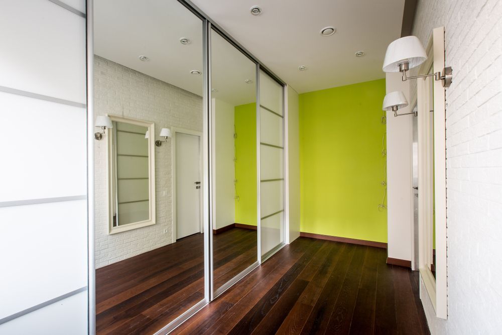 A Hallway With Sliding Mirrored Doors and a Green Wall — Glass 24/7 In Taree, NSW