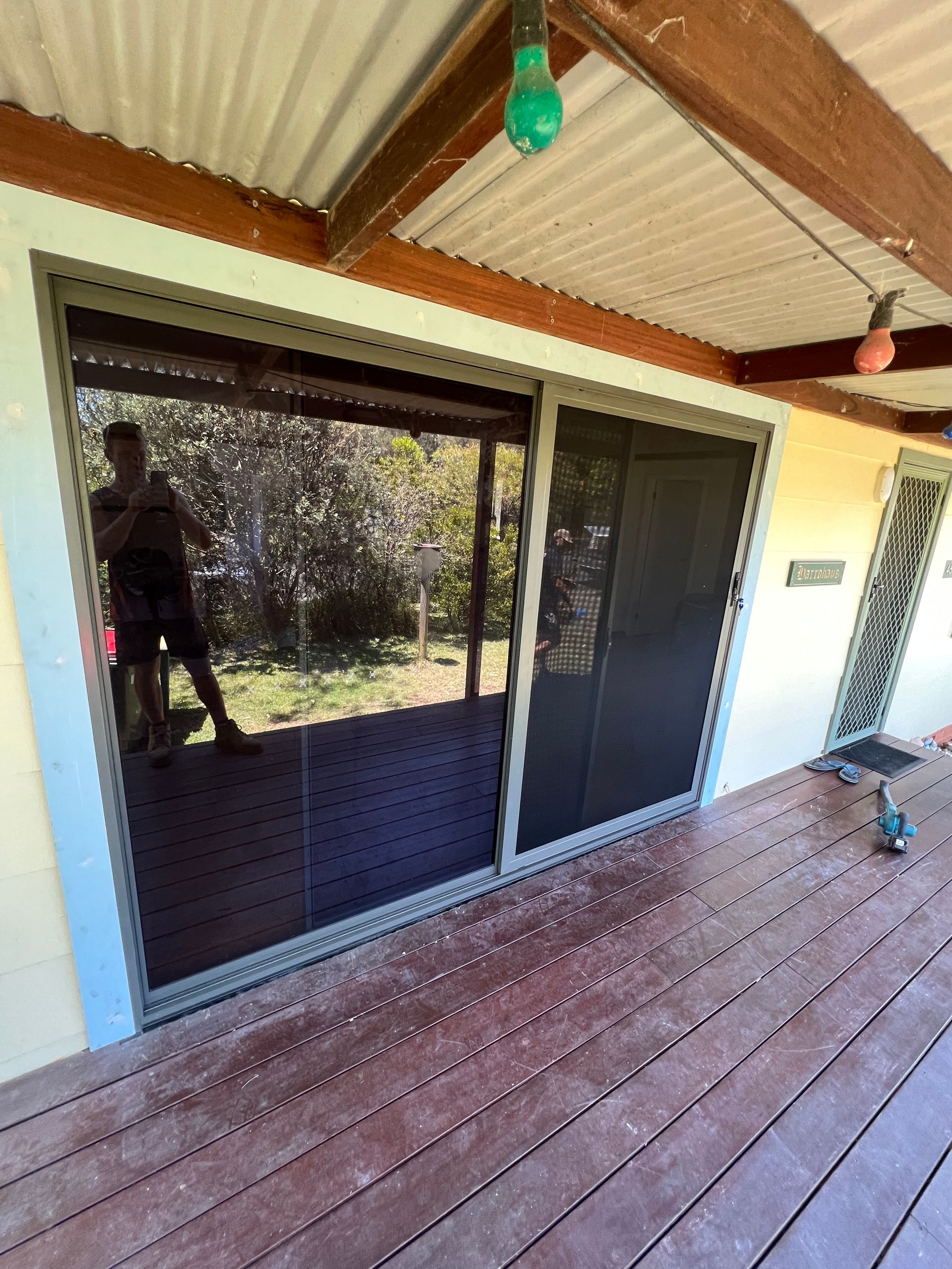 A person is standing in front of a sliding glass door on a deck — Glass 24/7 In Taree, NSW
