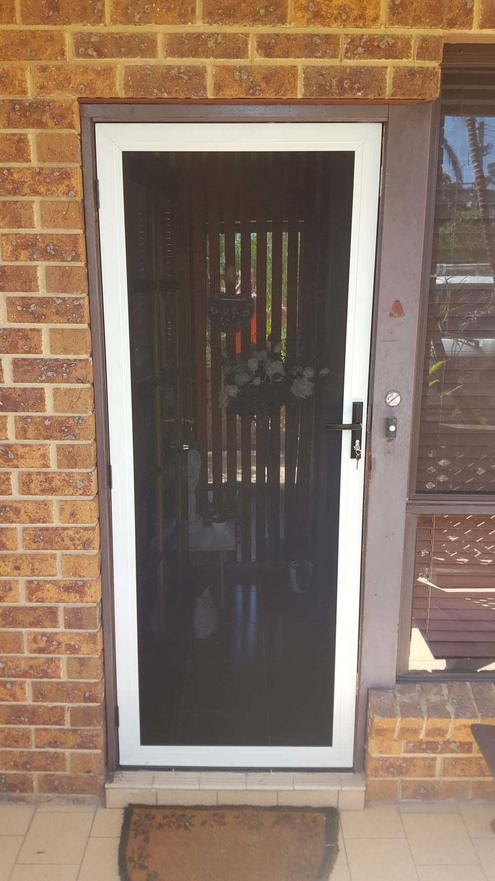 A White Screen Door Is Sitting On A Brick Wall — Glass 24/7 In Tuncurry, NSW