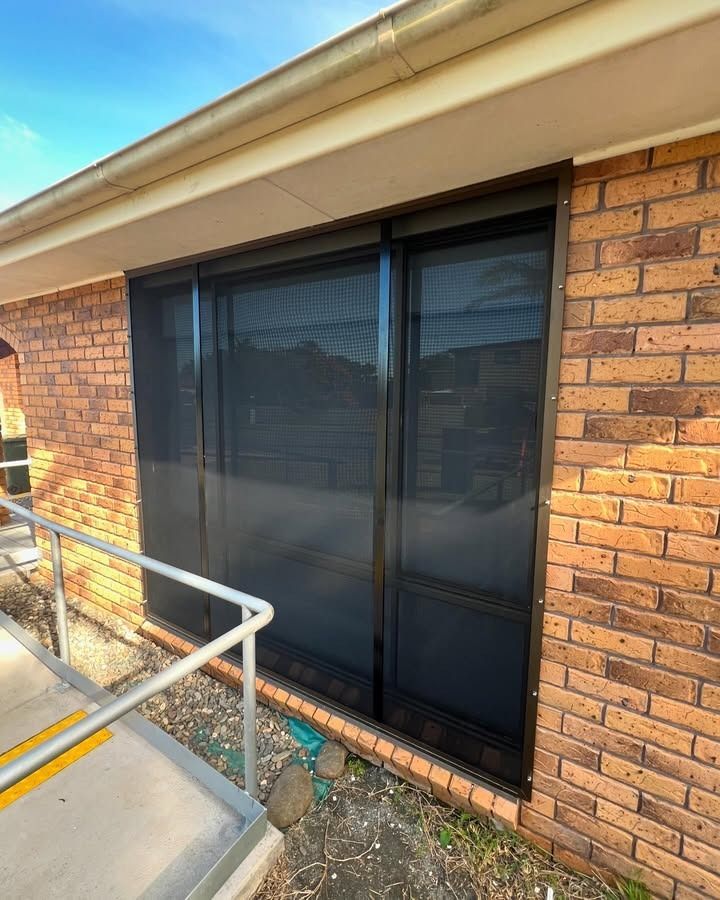 A Brick Building With A Sliding Glass Door And A Railing — Glass 24/7 In Pacific Palms, NSW