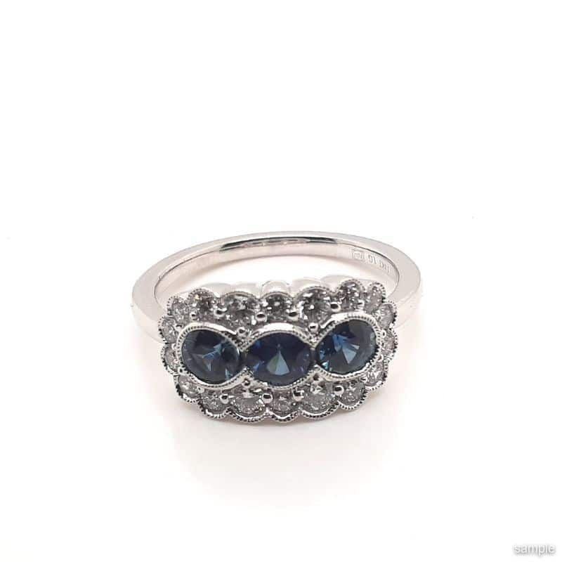 Silver ring with three dark blue stones surrounded by smaller clear stones.