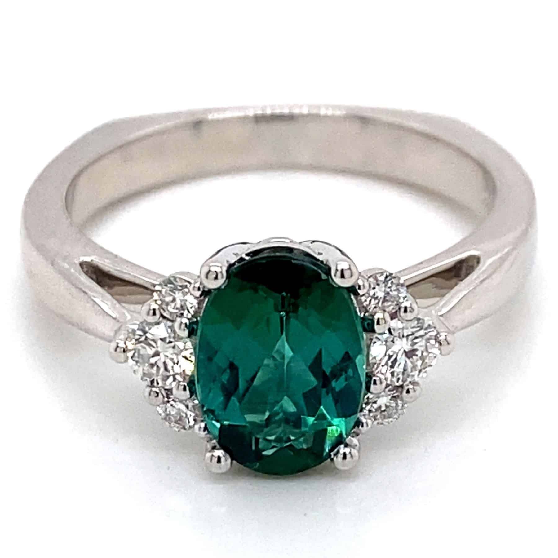White gold ring with a green oval-cut gemstone and diamond accents.