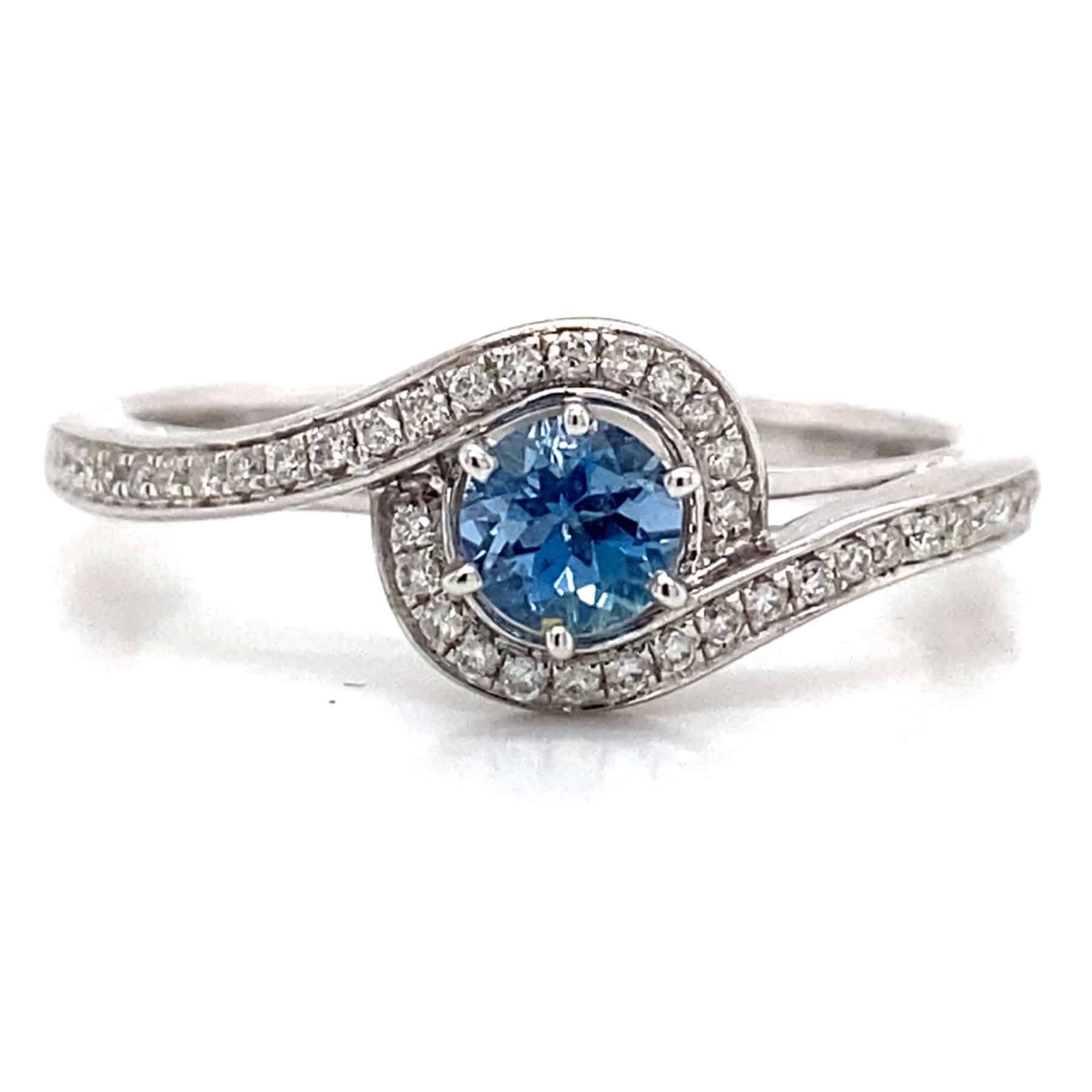 Swirling silver ring with a round blue gemstone surrounded by small diamonds.