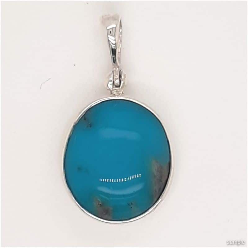 Turquoise pendant with a silver setting and bail. Blue gemstone with dark spots.