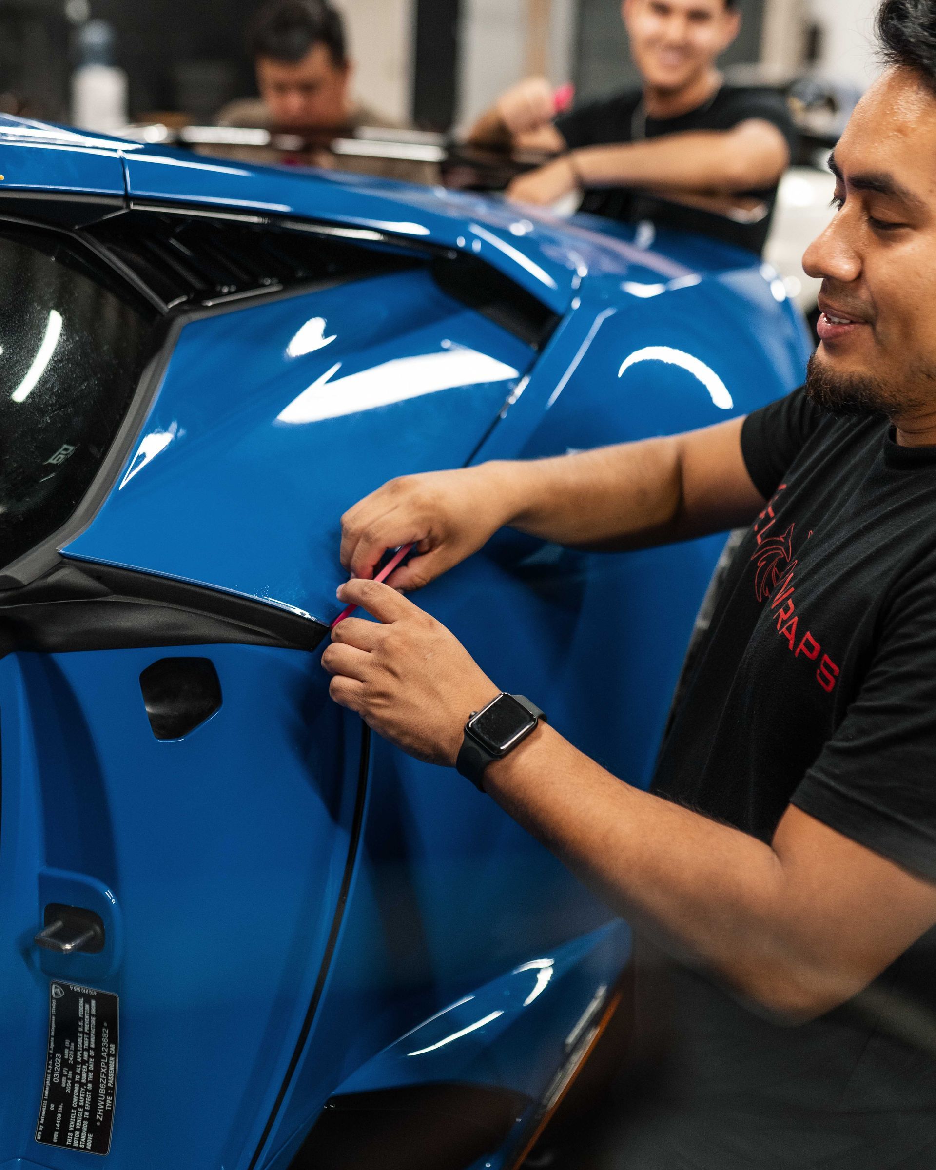 A man in a black shirt is working on a blue car