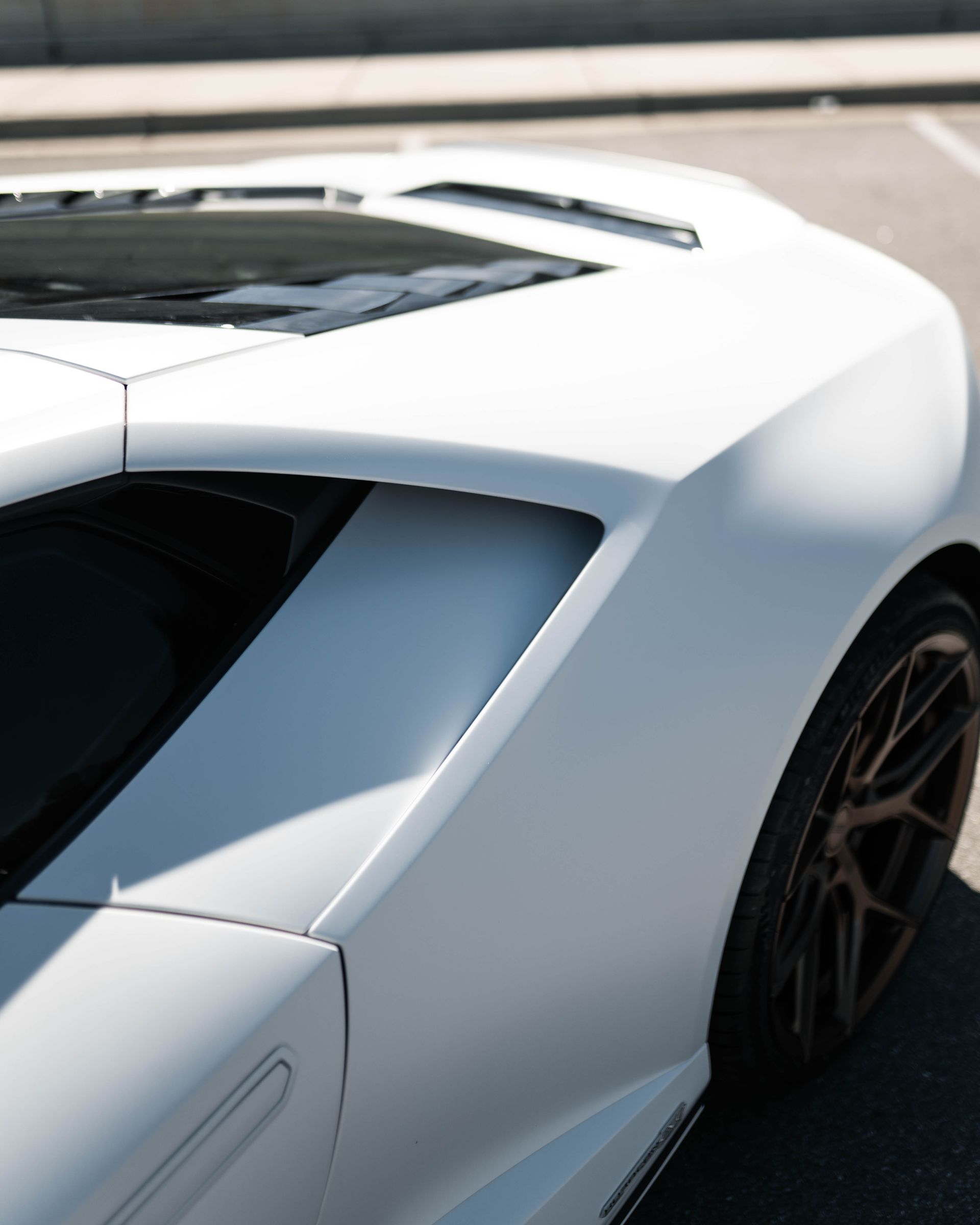A white sports car is parked on the side of the road