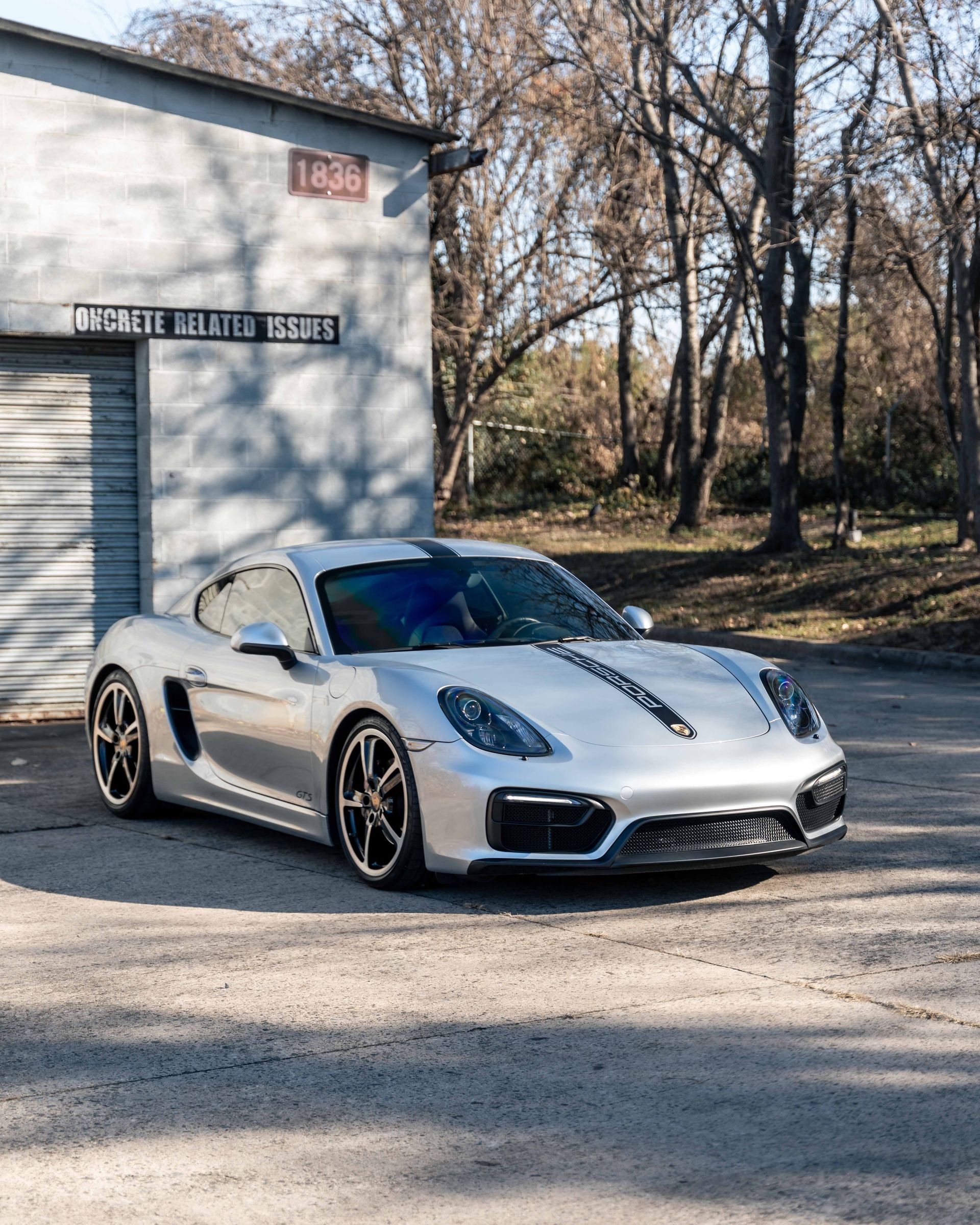 A silver sports car is parked in front of a garage.