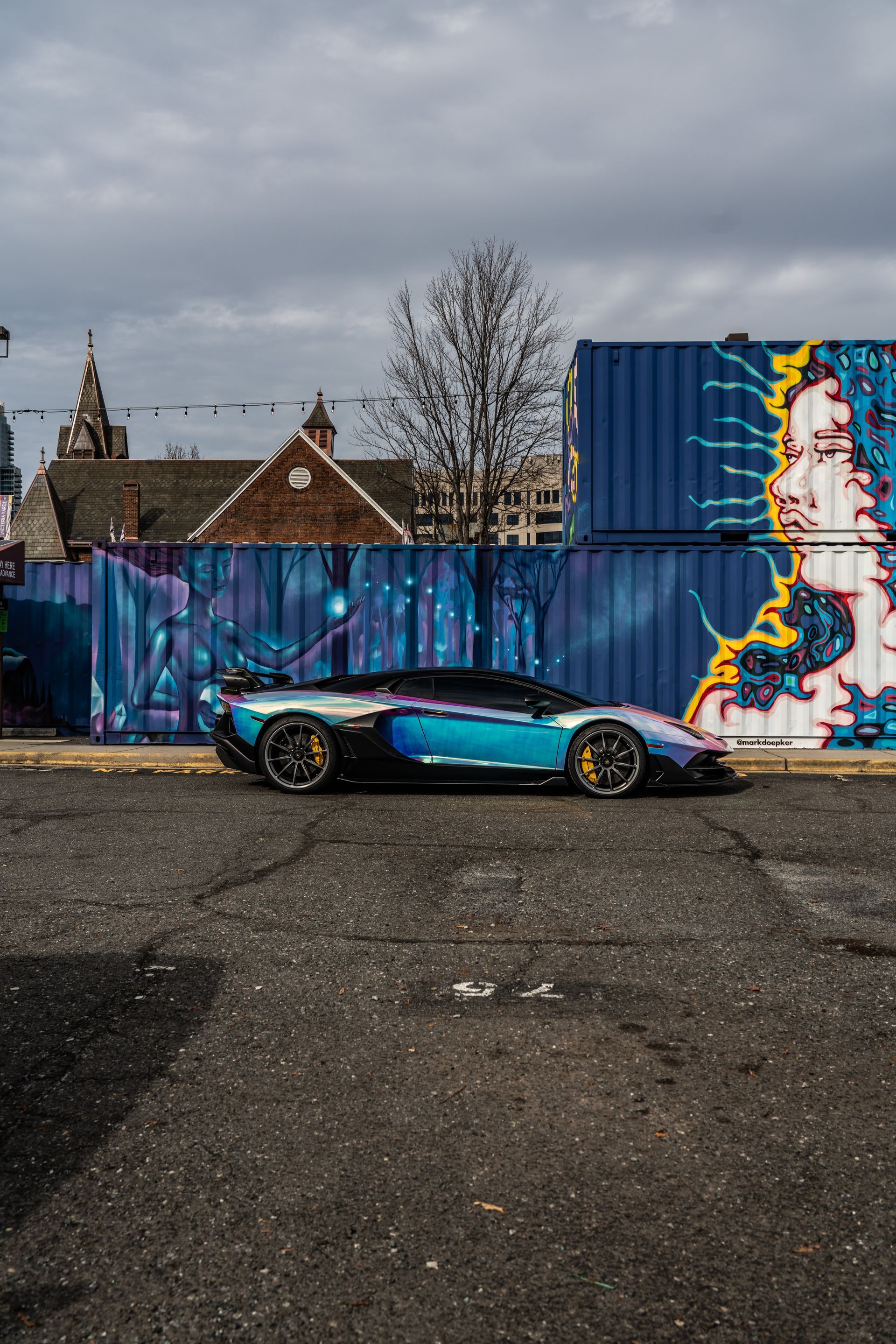 A sports car is parked in front of a graffiti covered wall.