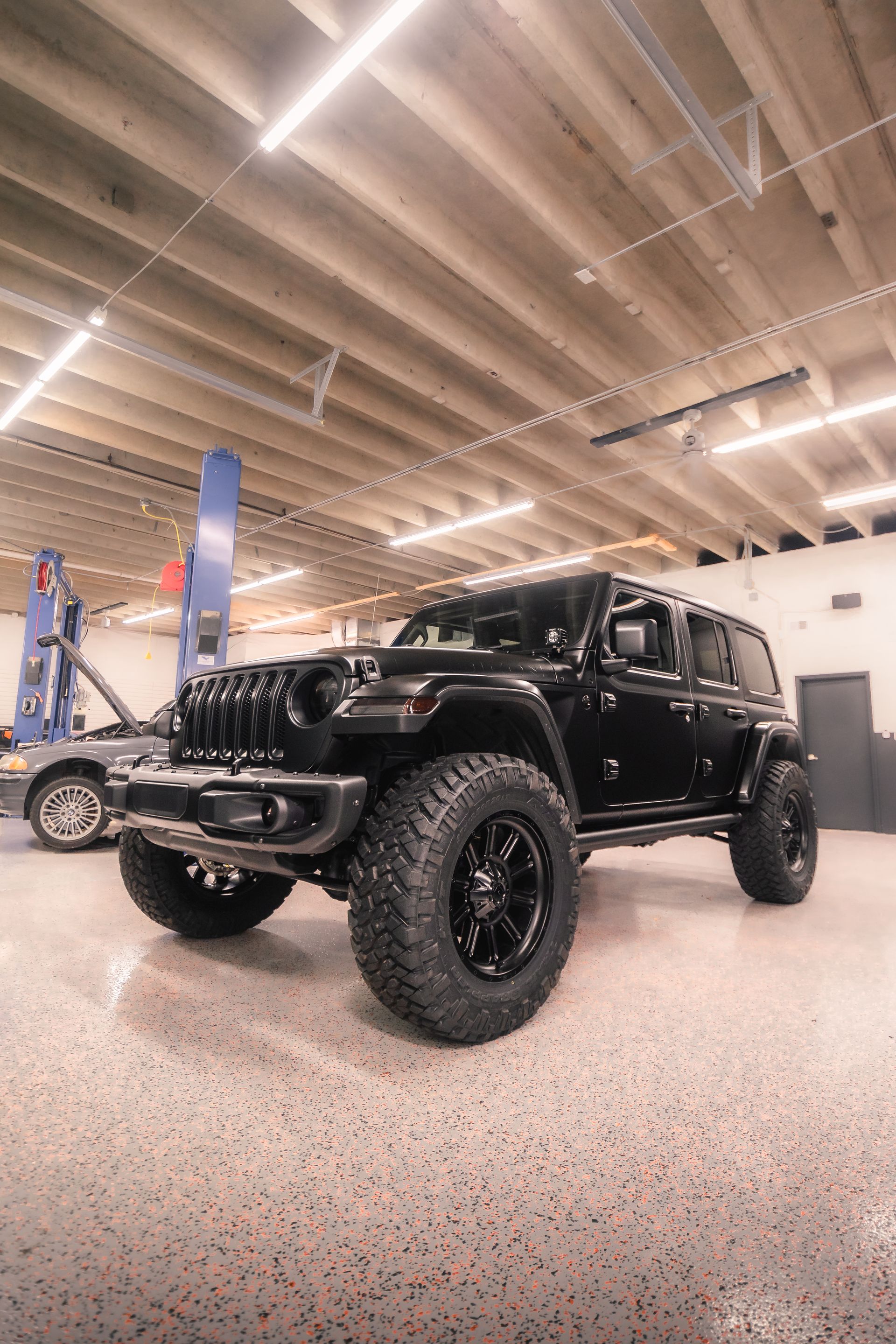 A black jeep is parked in a garage.
