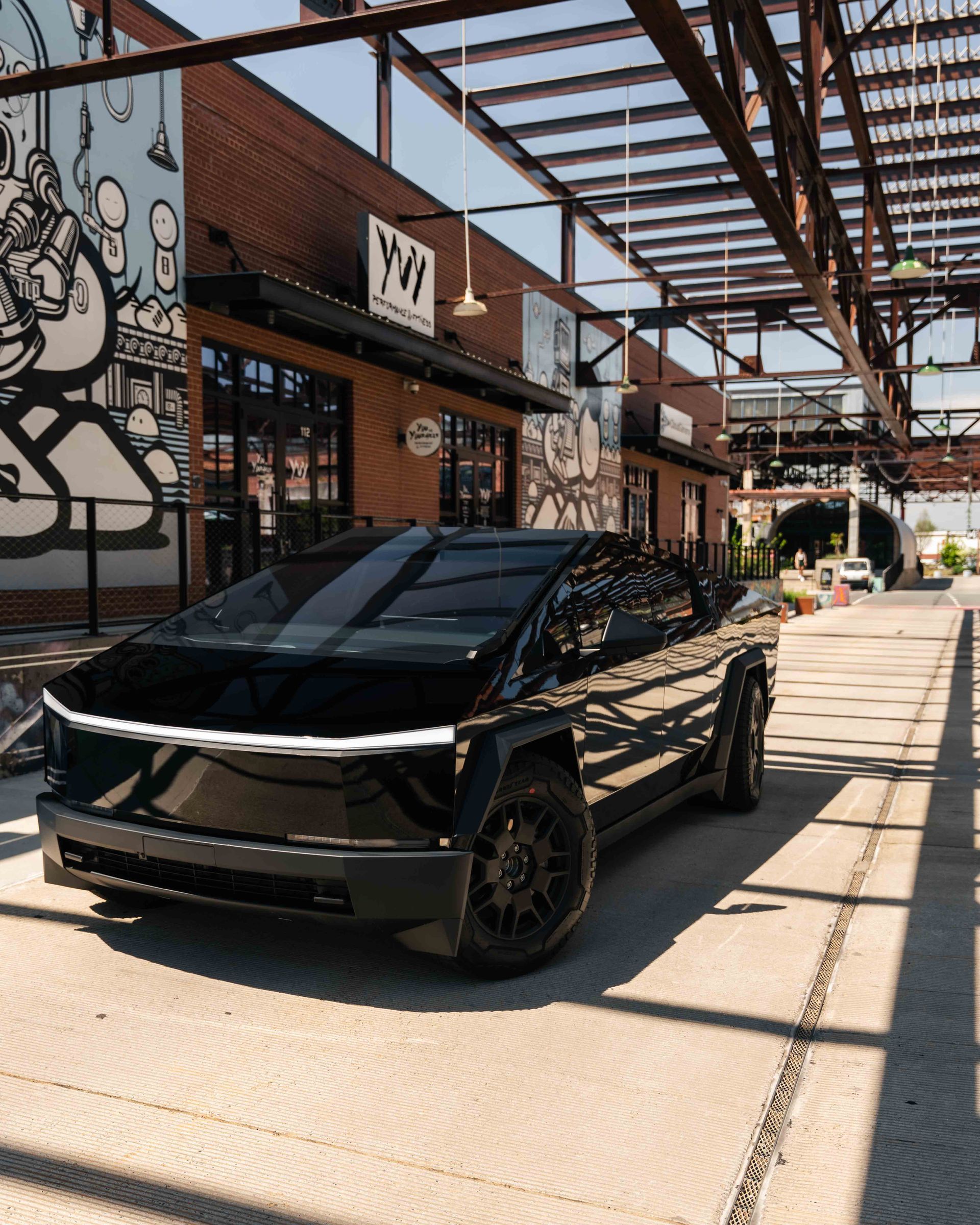 A black car is parked in front of a brick building