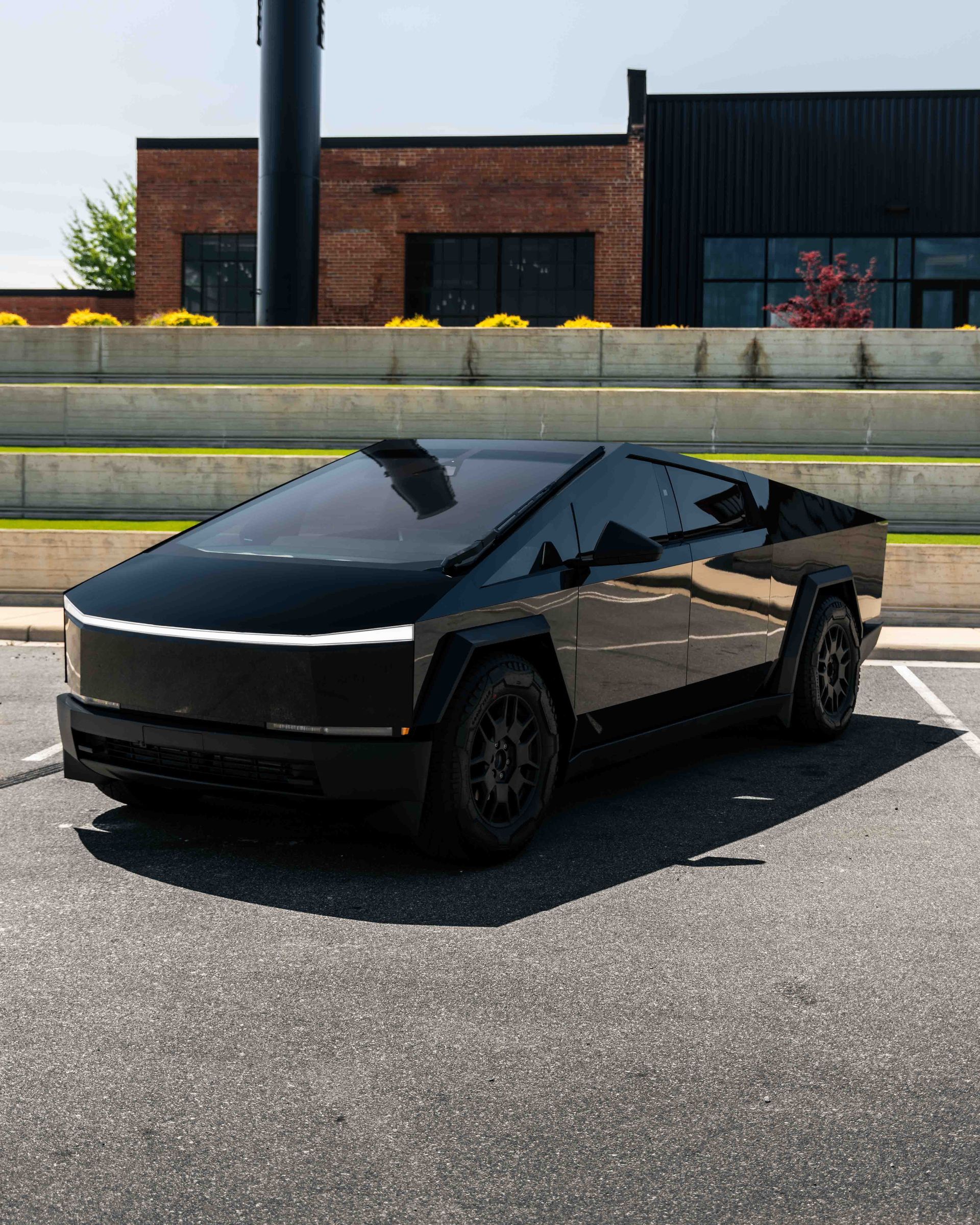 A black car is parked in a parking lot in front of a building.