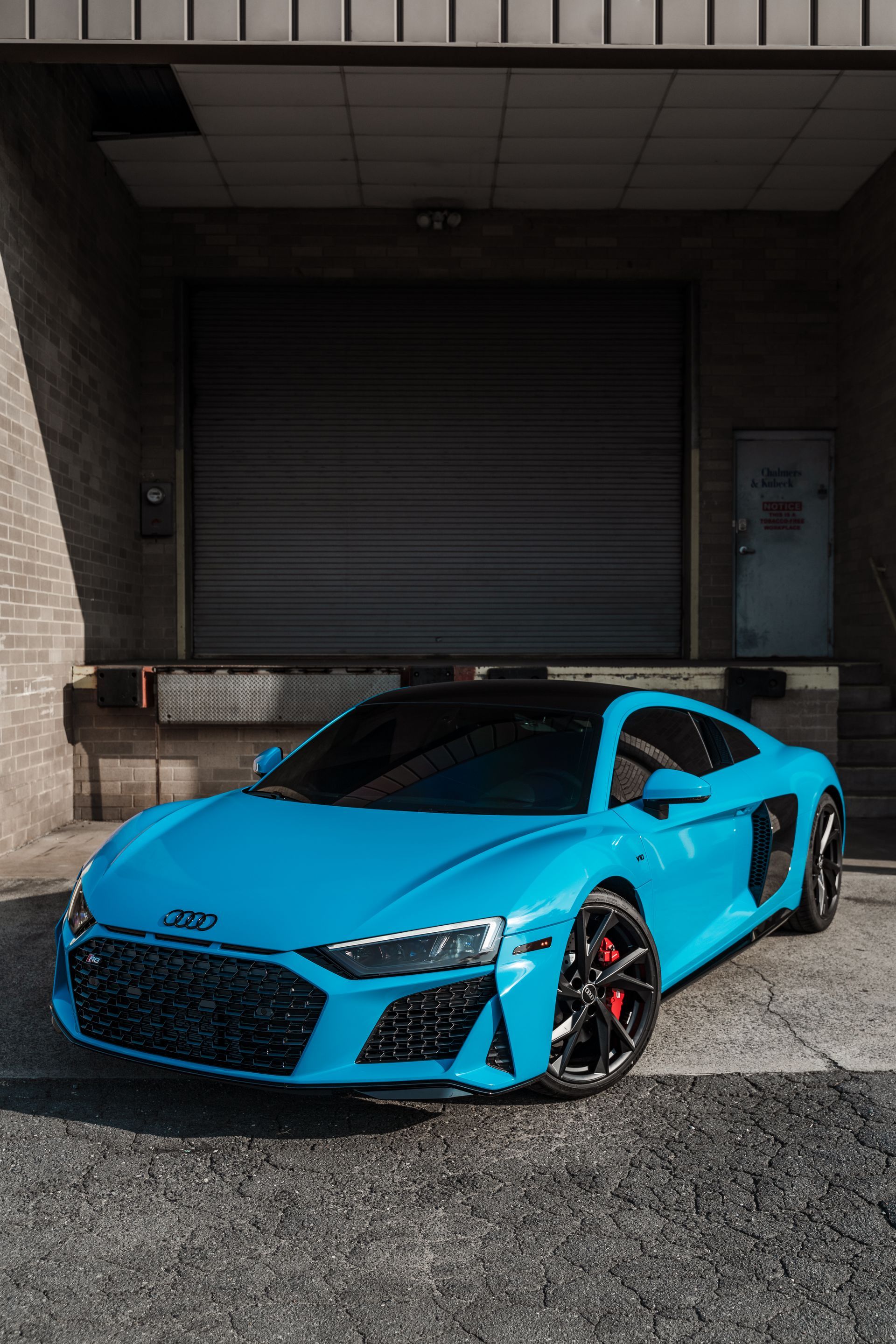 A blue audi r8 is parked in front of a building.