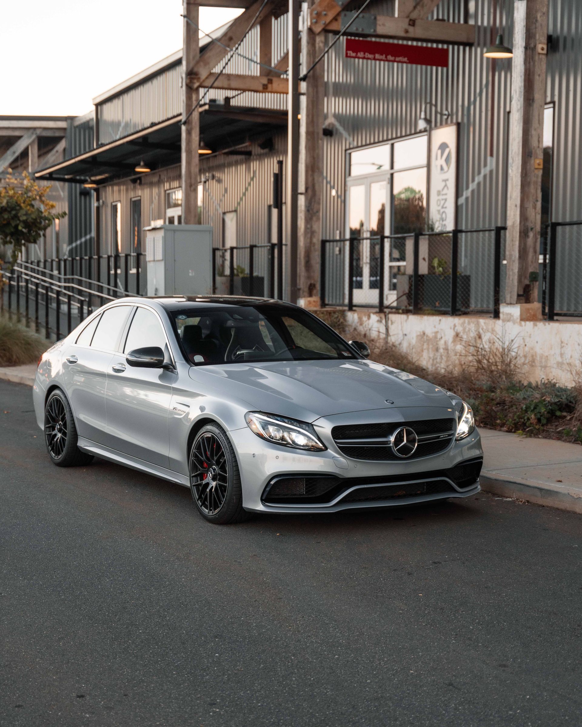 A silver mercedes is parked on the side of the road