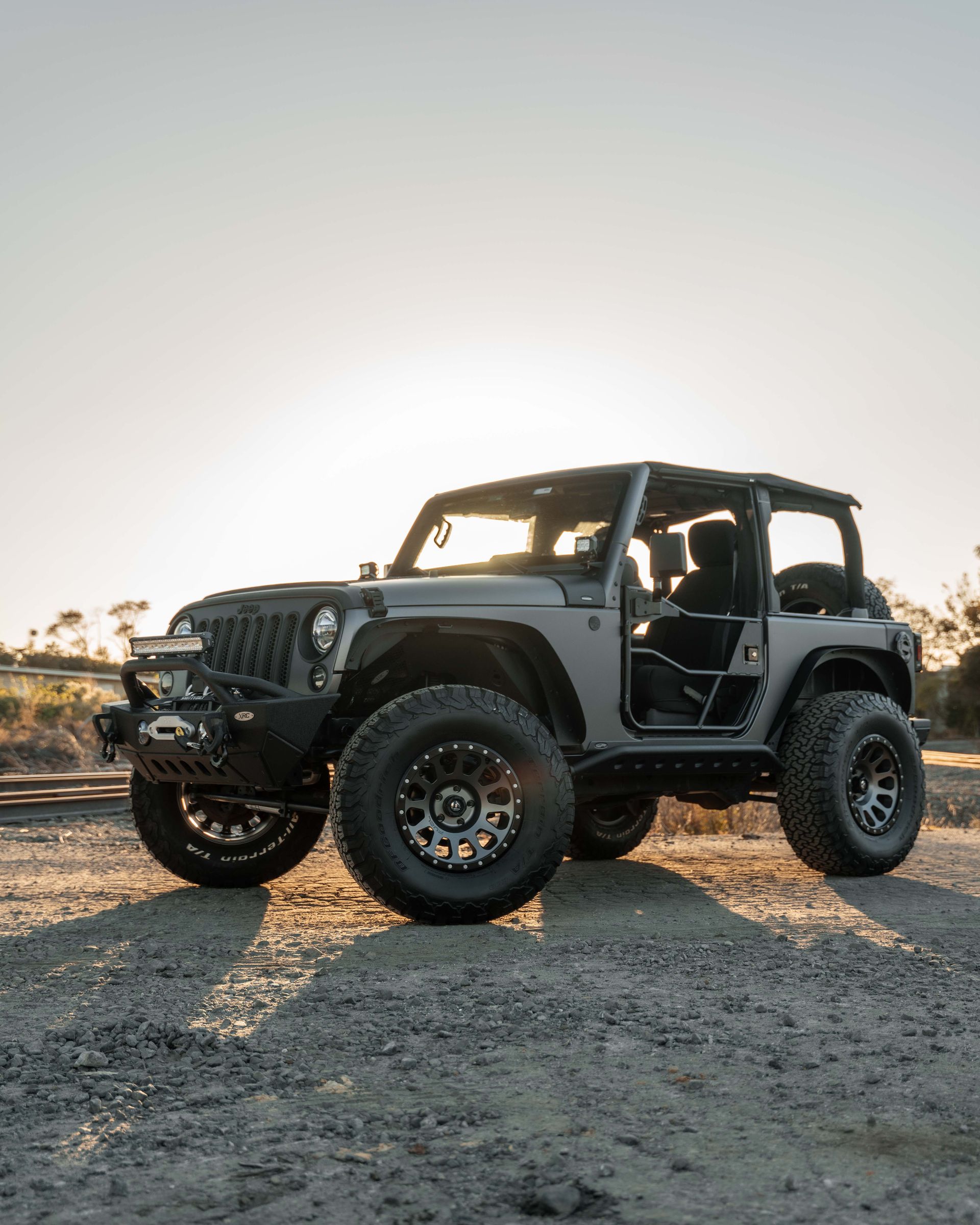 A jeep is parked in the dirt on a dirt road.