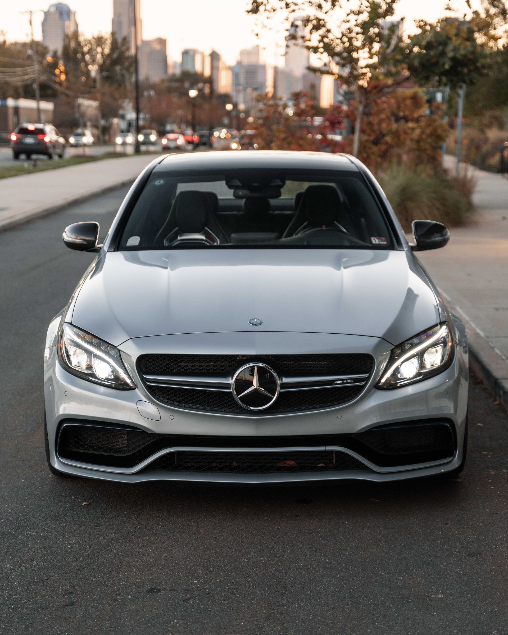 A silver mercedes is parked on the side of the road