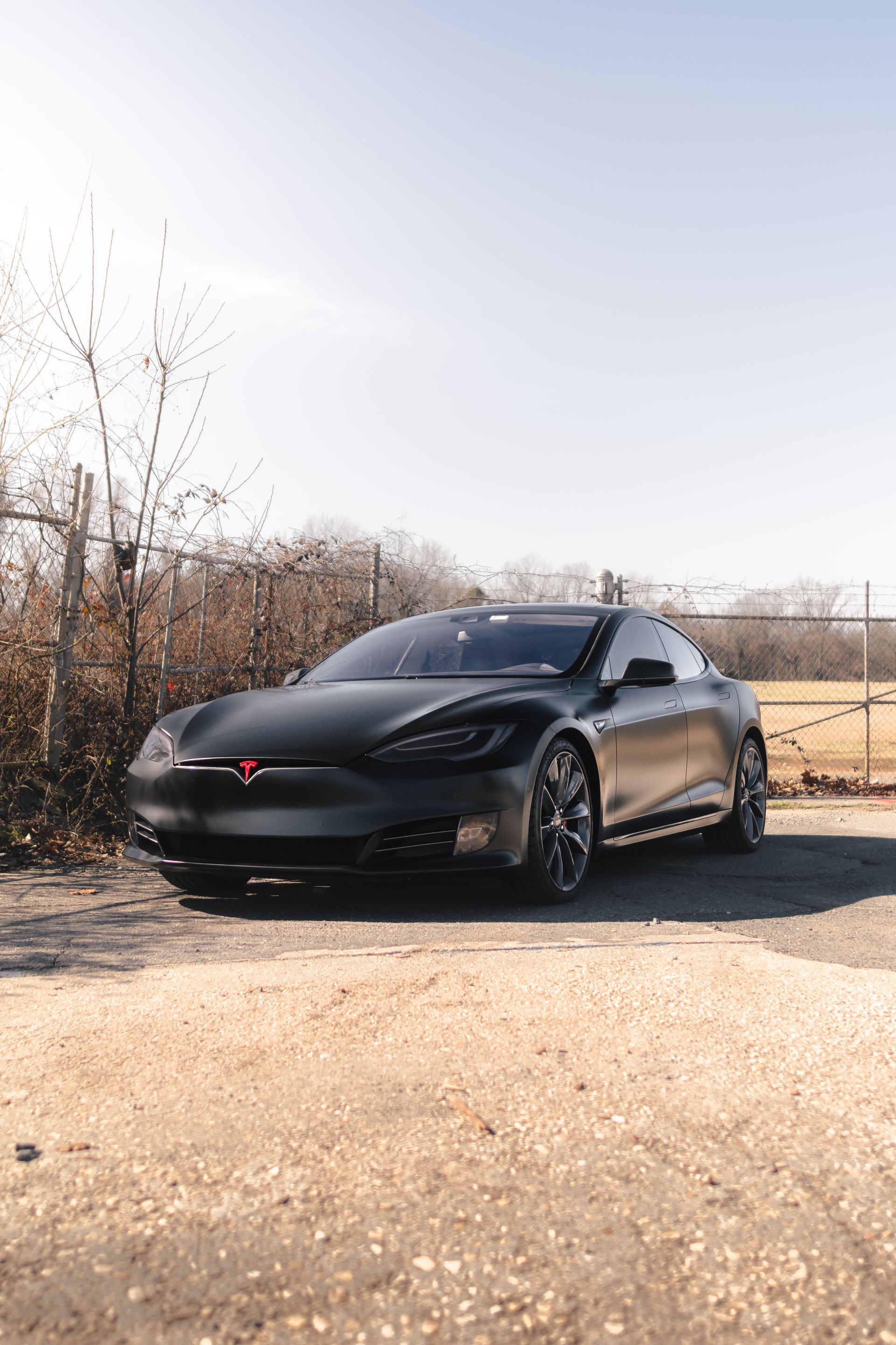 A black tesla model s is parked on the side of the road.