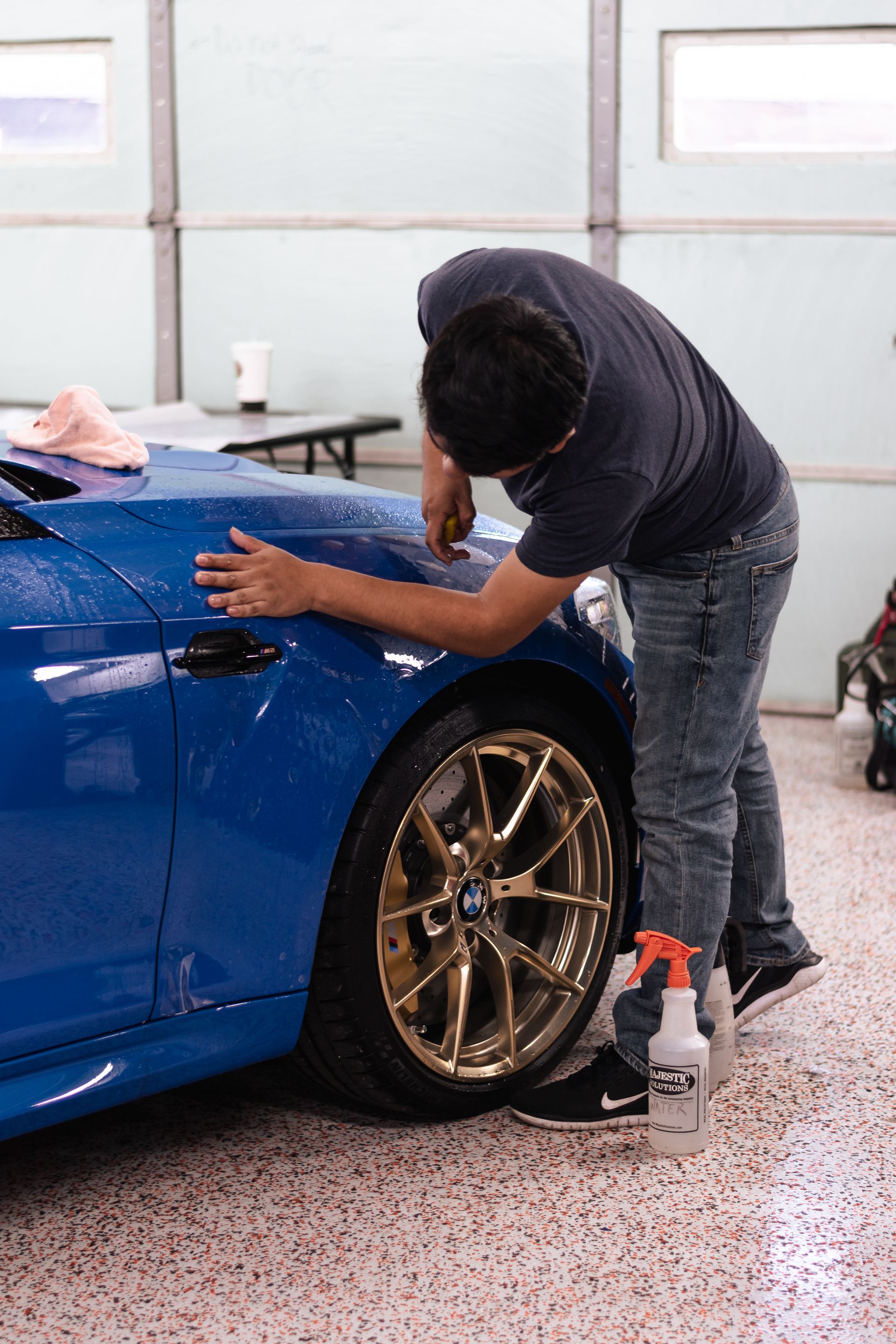 A man is cleaning a blue car in a garage.