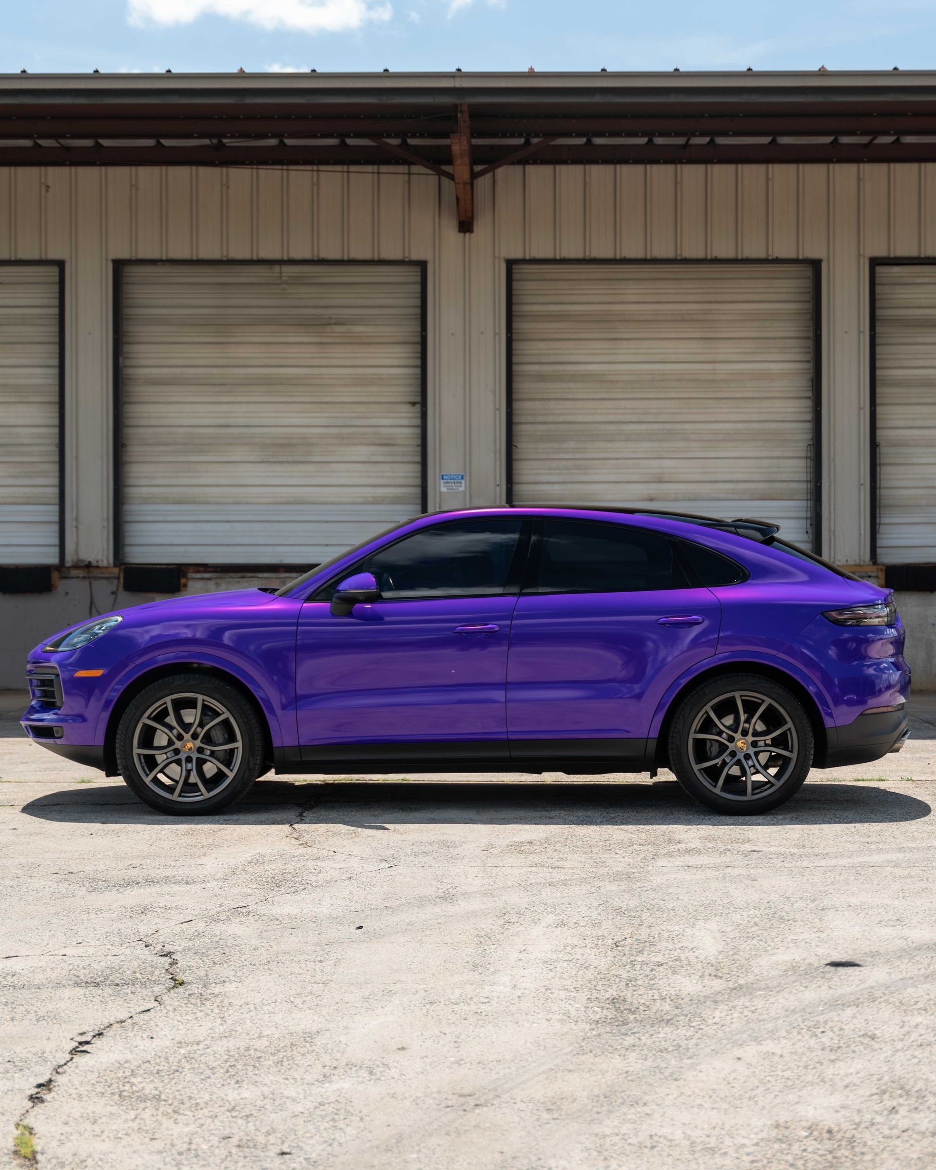 A purple car is parked in front of a building