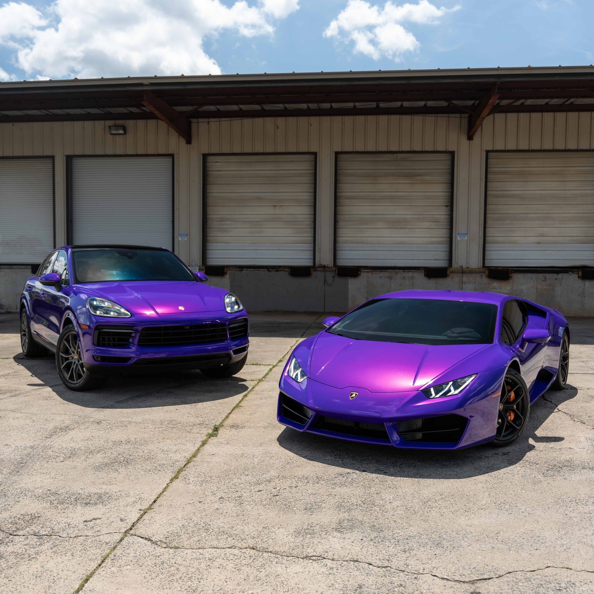 Two purple cars are parked next to each other in front of a building.