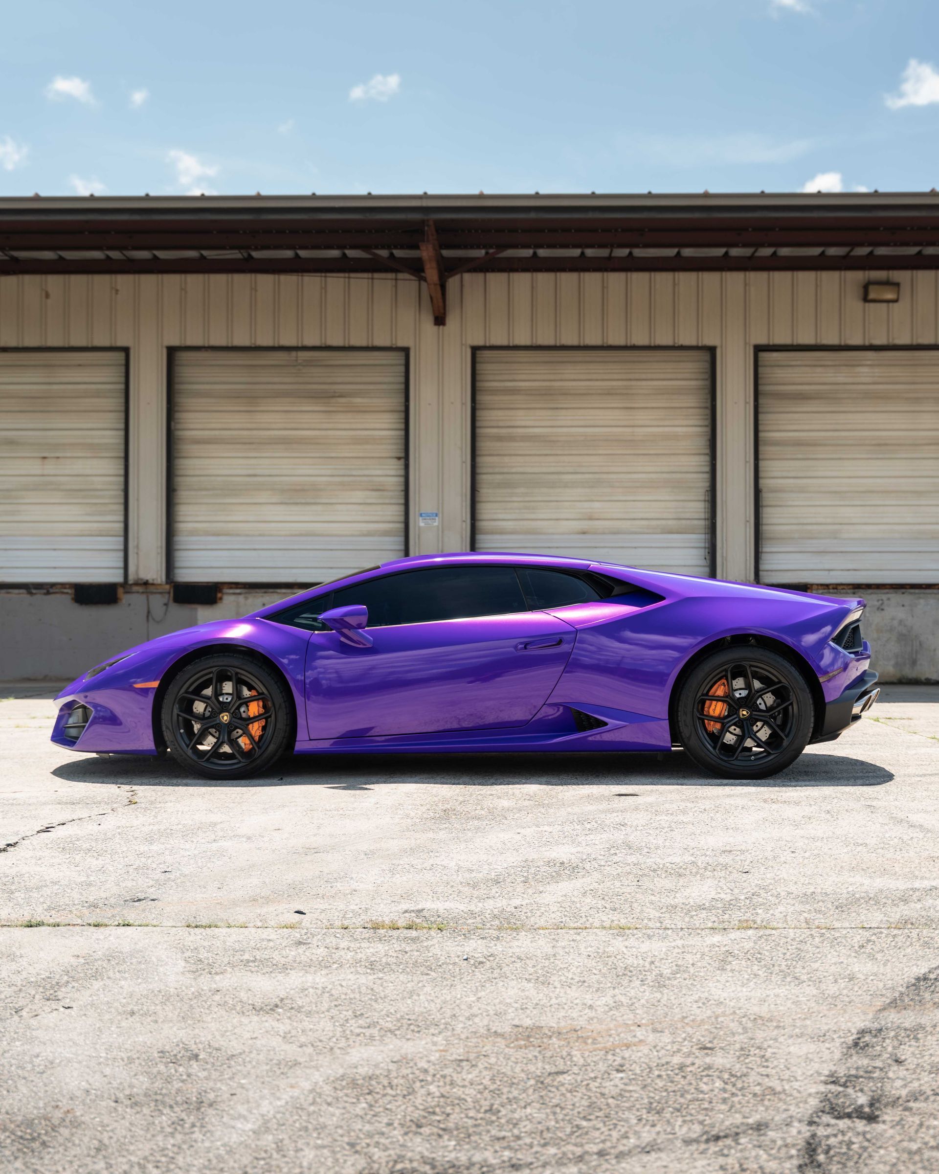 A purple sports car is parked in front of a building