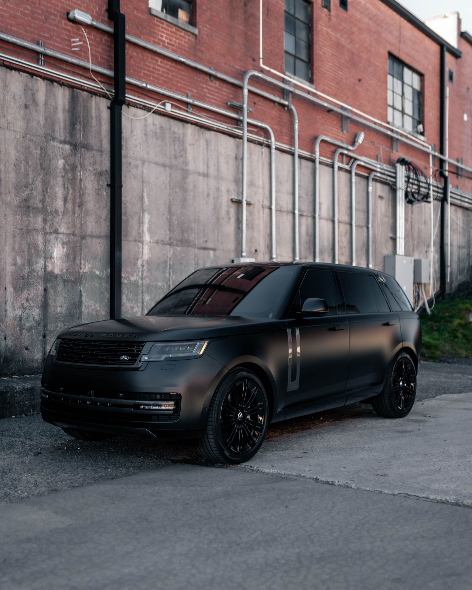 A black car is parked in front of a brick building