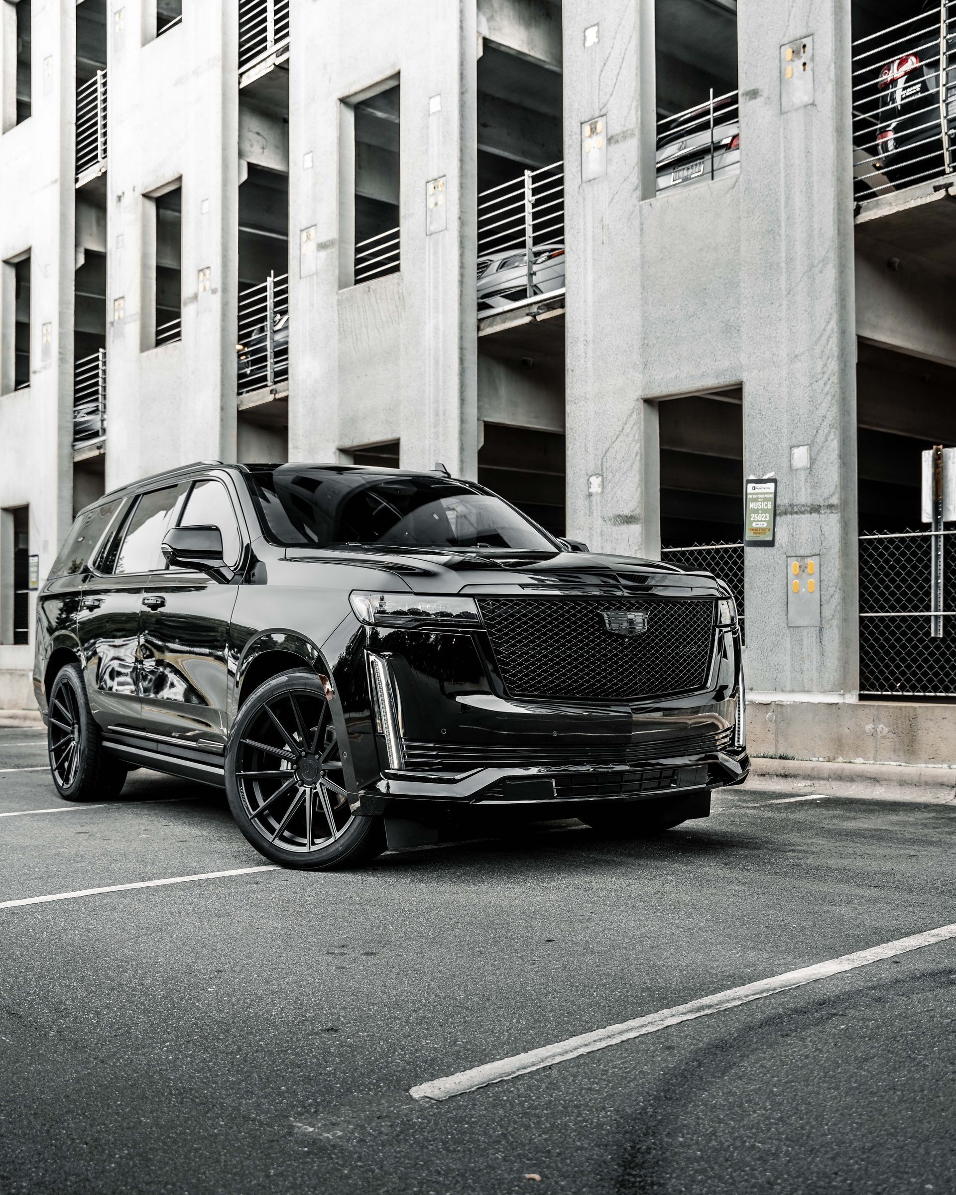 A black suv is parked in a parking lot in front of a building.