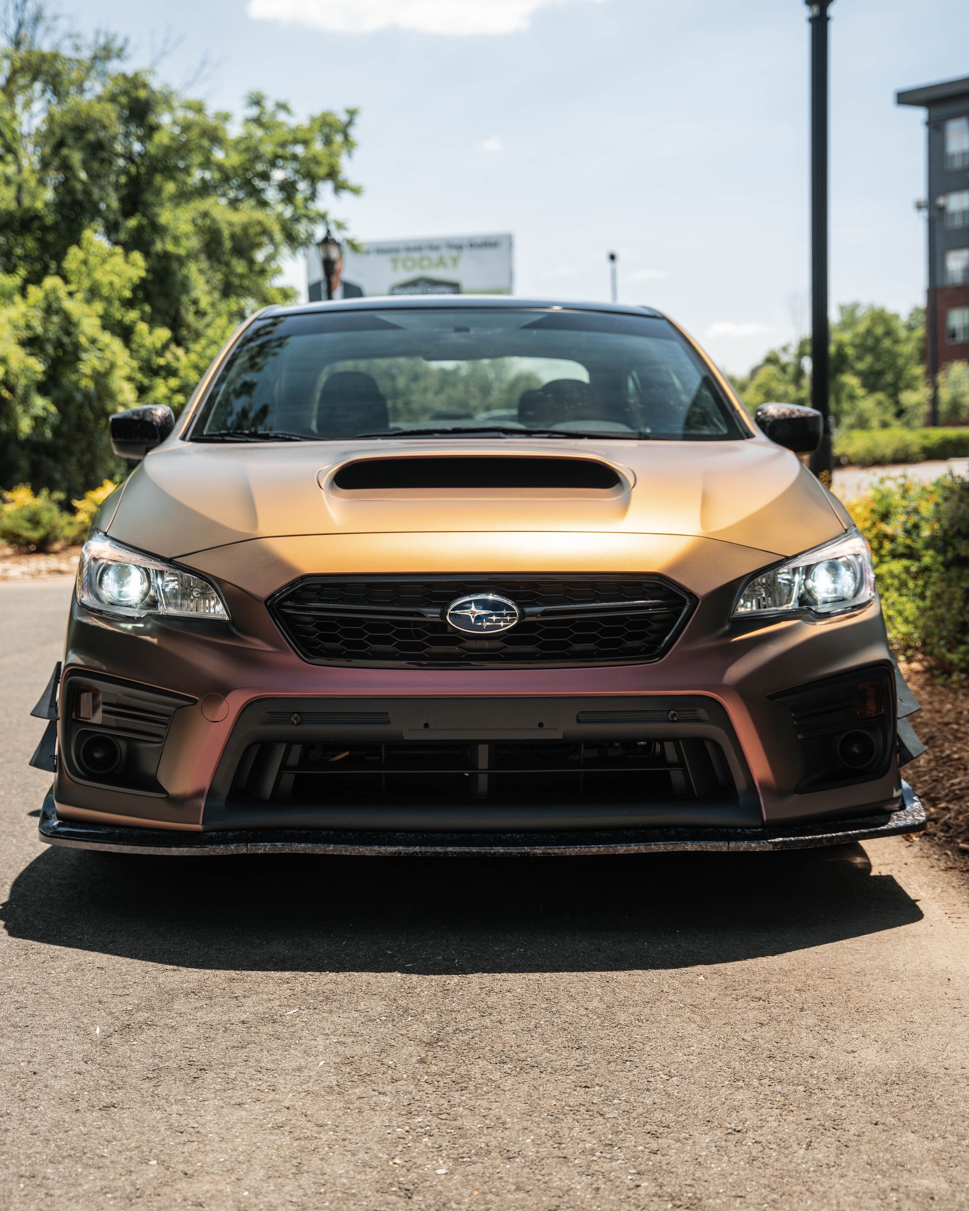 A gold subaru is parked on the side of the road