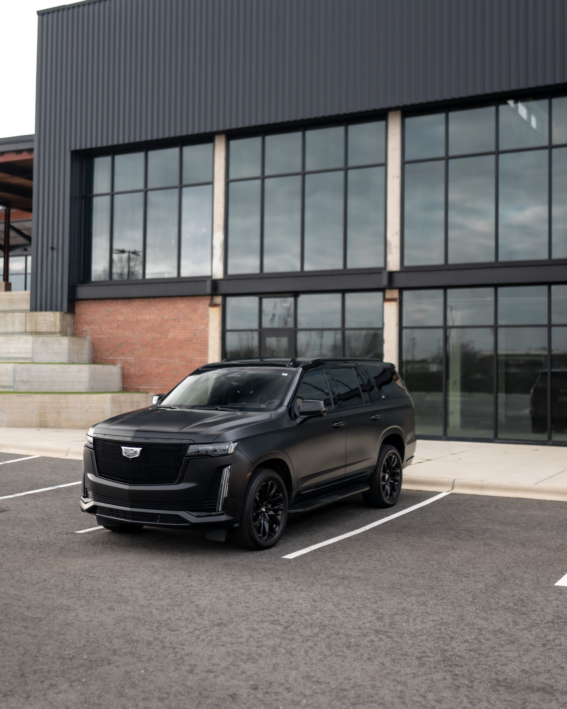 A black suv is parked in front of a building with lots of windows