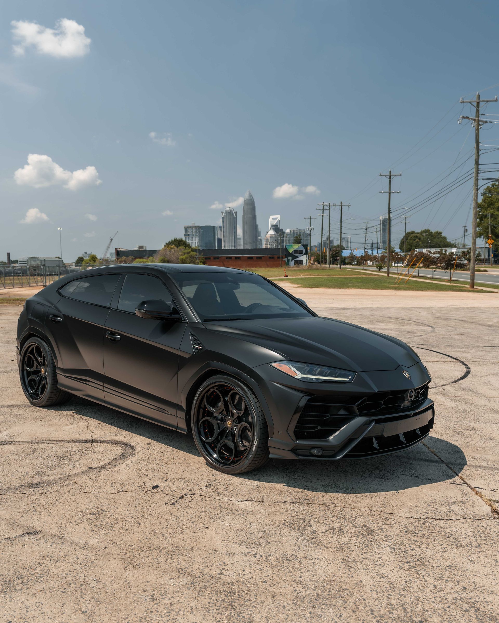 A black lamborghini urus is parked in a parking lot.