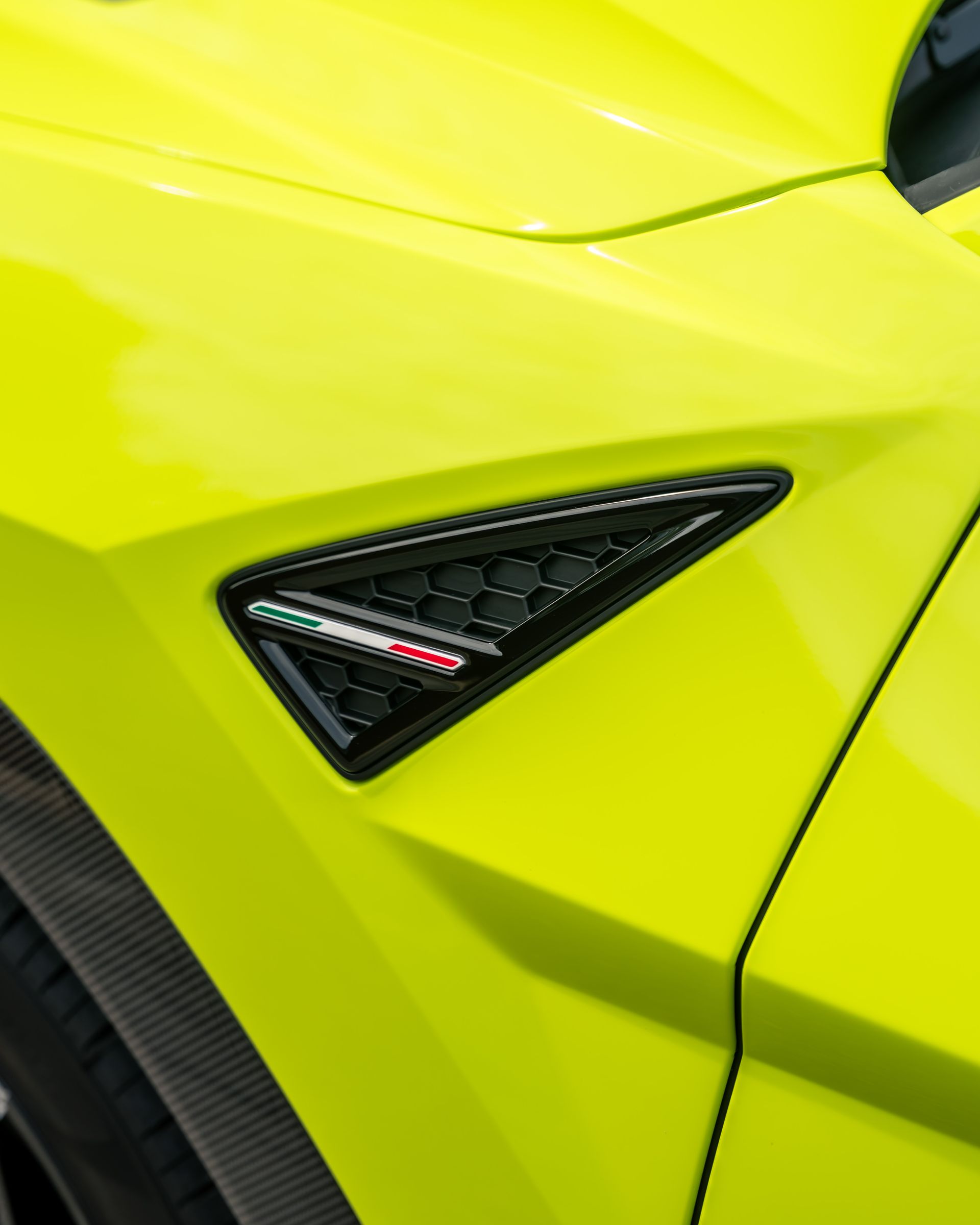 A close up of a yellow car with a black emblem on the side.