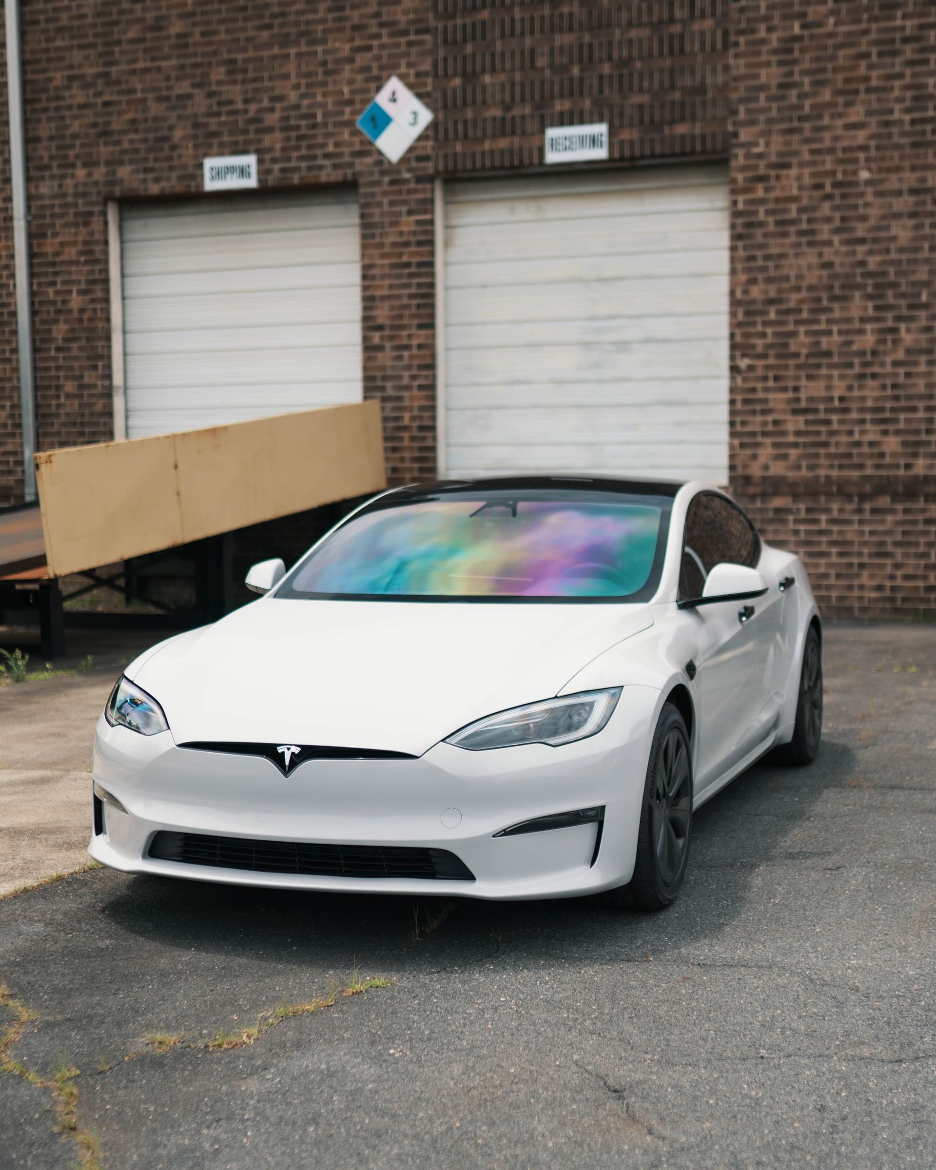 A white tesla model s is parked in front of a brick building