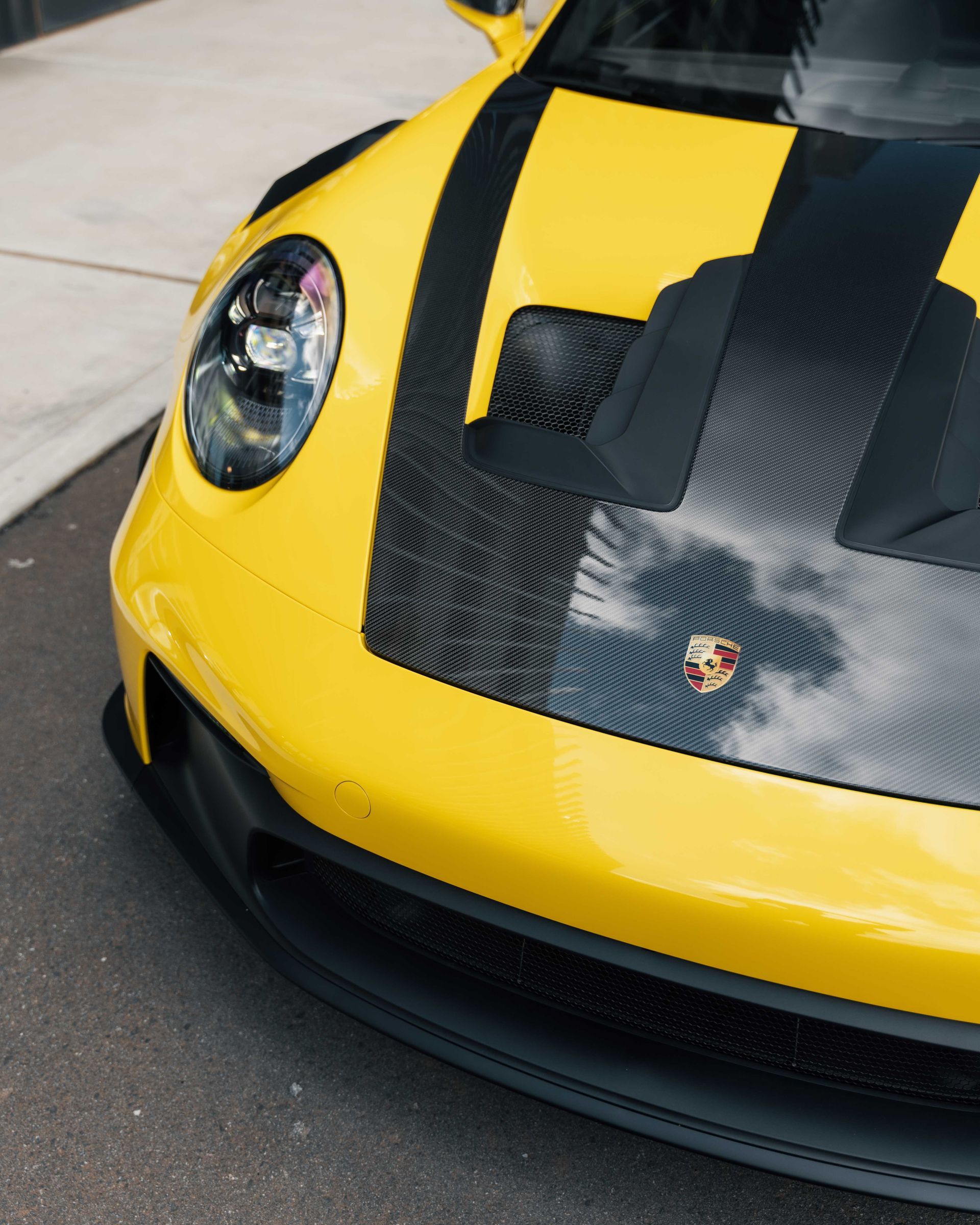 A yellow sports car with black stripes on the hood