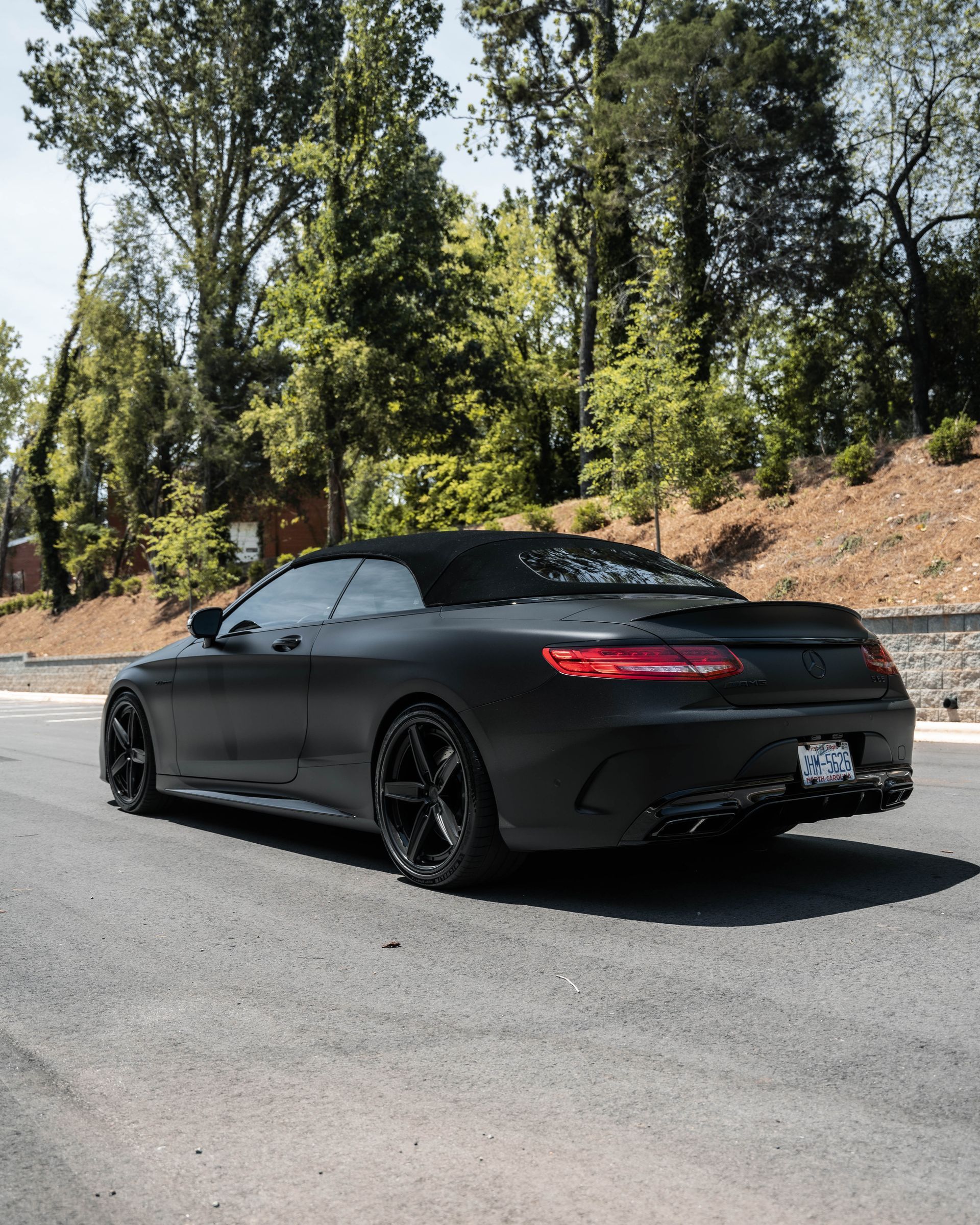 A black sports car with a convertible top is parked on the side of the road.