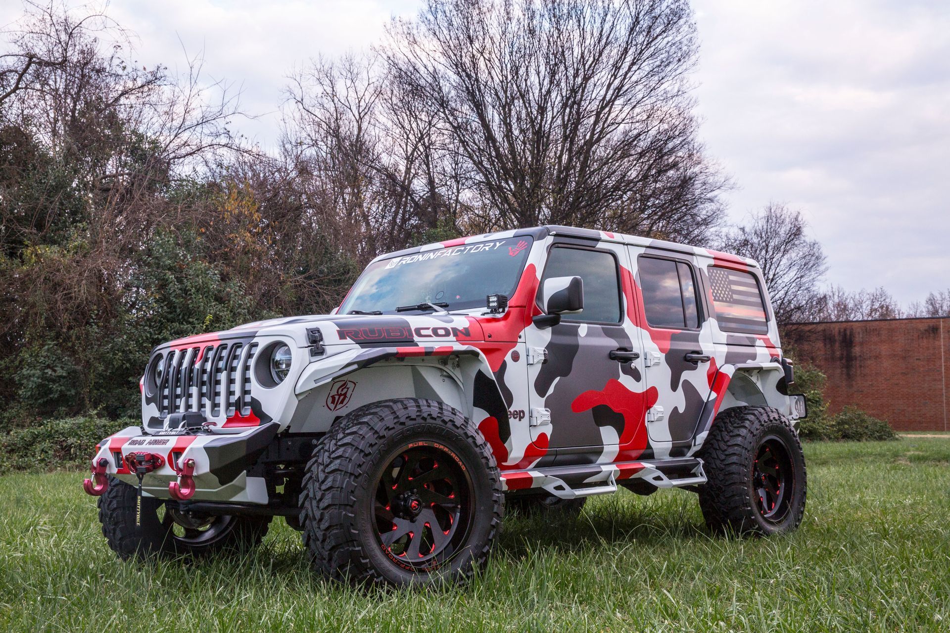A camouflaged jeep is parked in a grassy field.