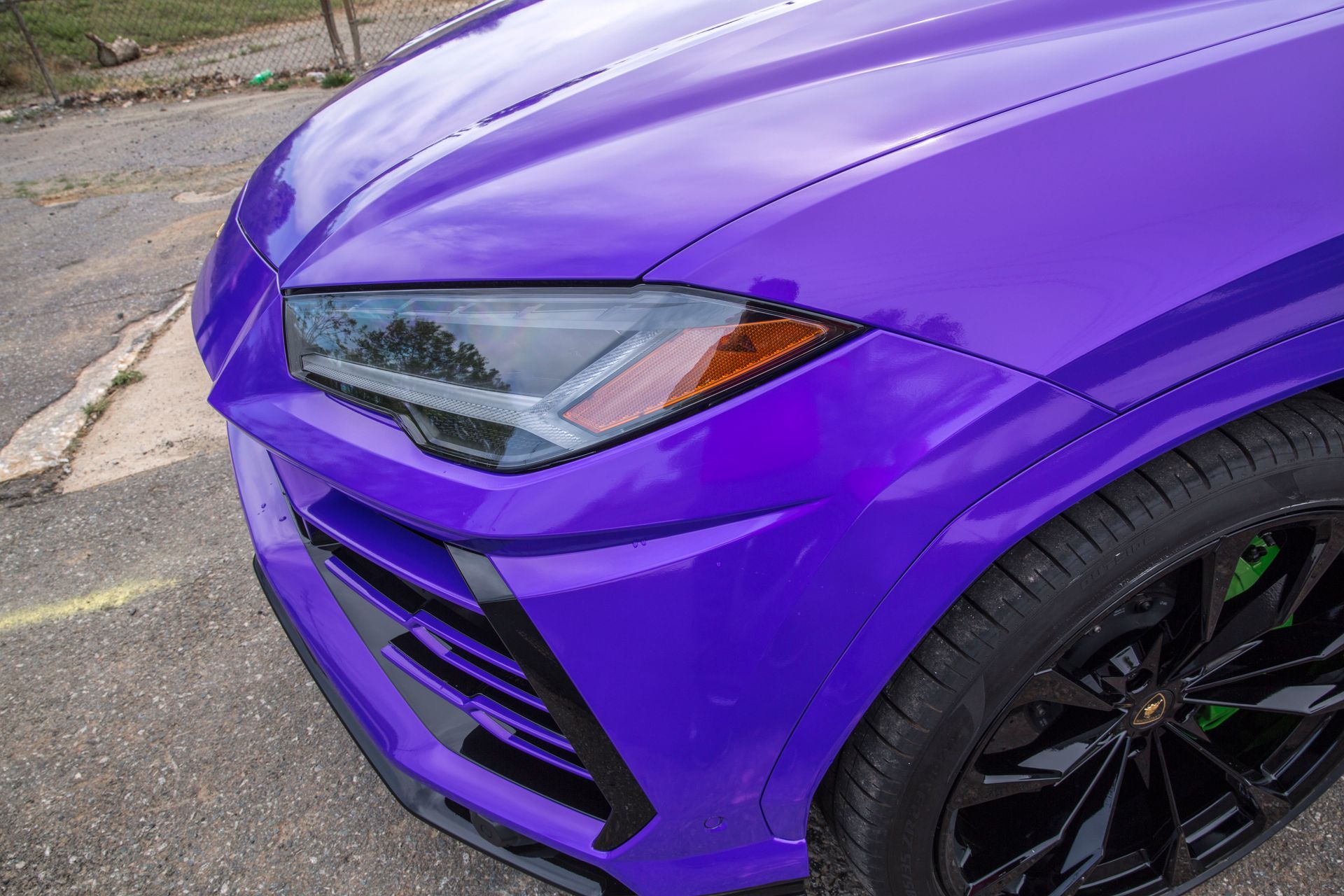 A purple lamborghini urus is parked in a parking lot.