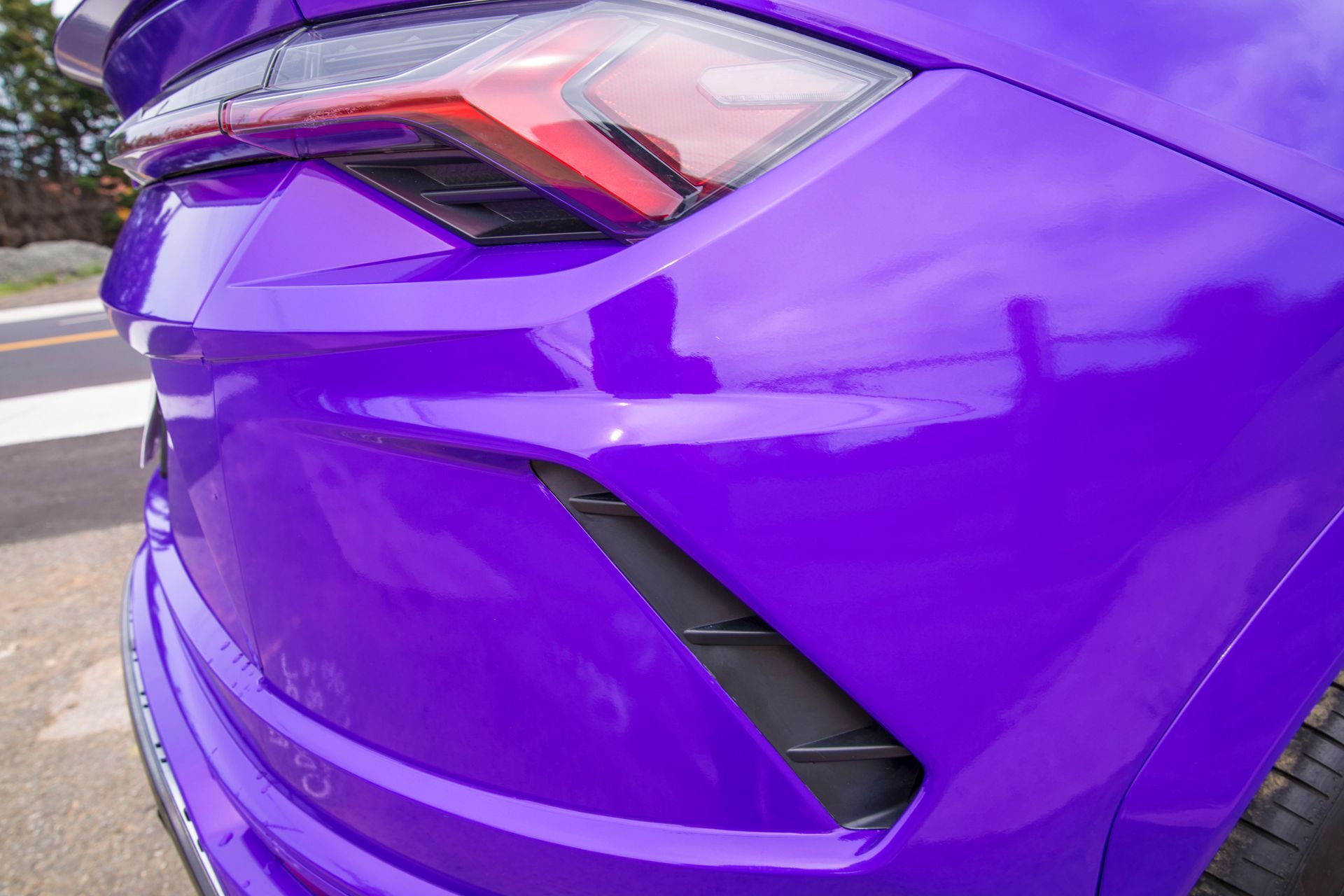 A purple lamborghini urus is parked on the side of the road.