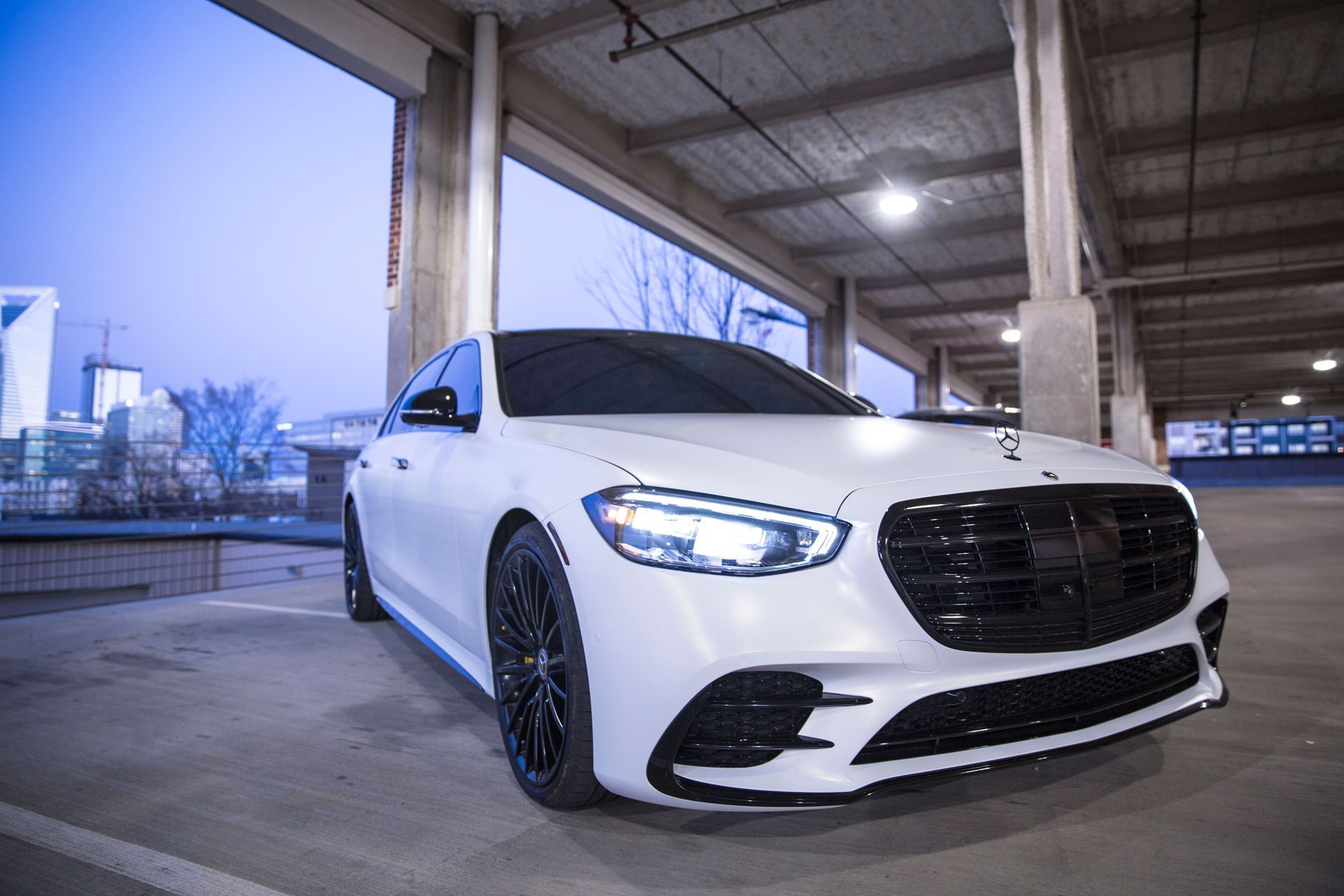 A white mercedes benz is parked in a parking garage.