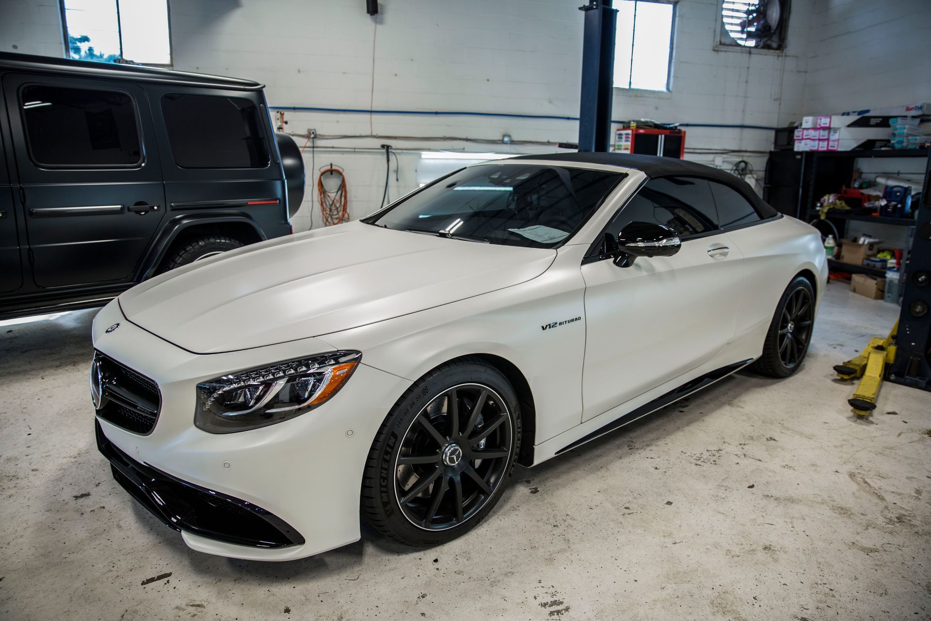 A white mercedes benz s63 amg convertible is parked in a garage.