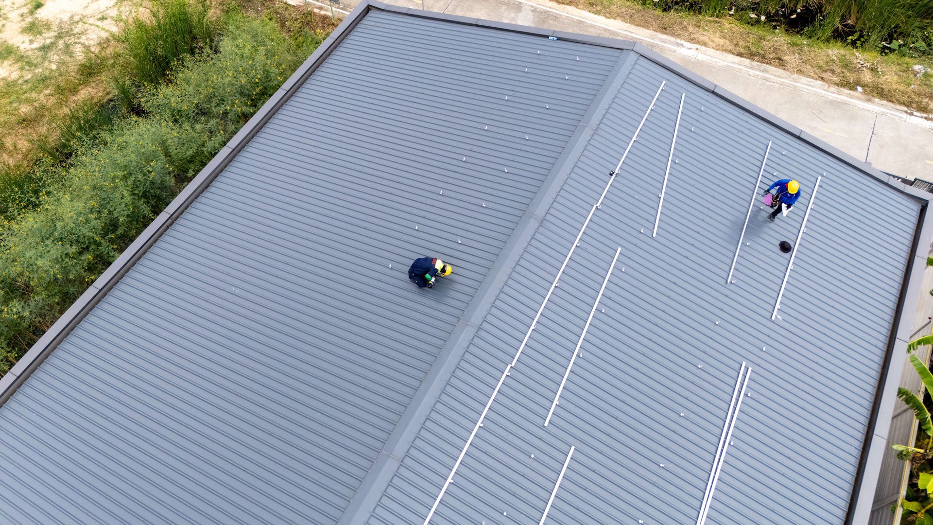 Building with dark gray corrugated roof and black gutters. Yellow exterior, windows.