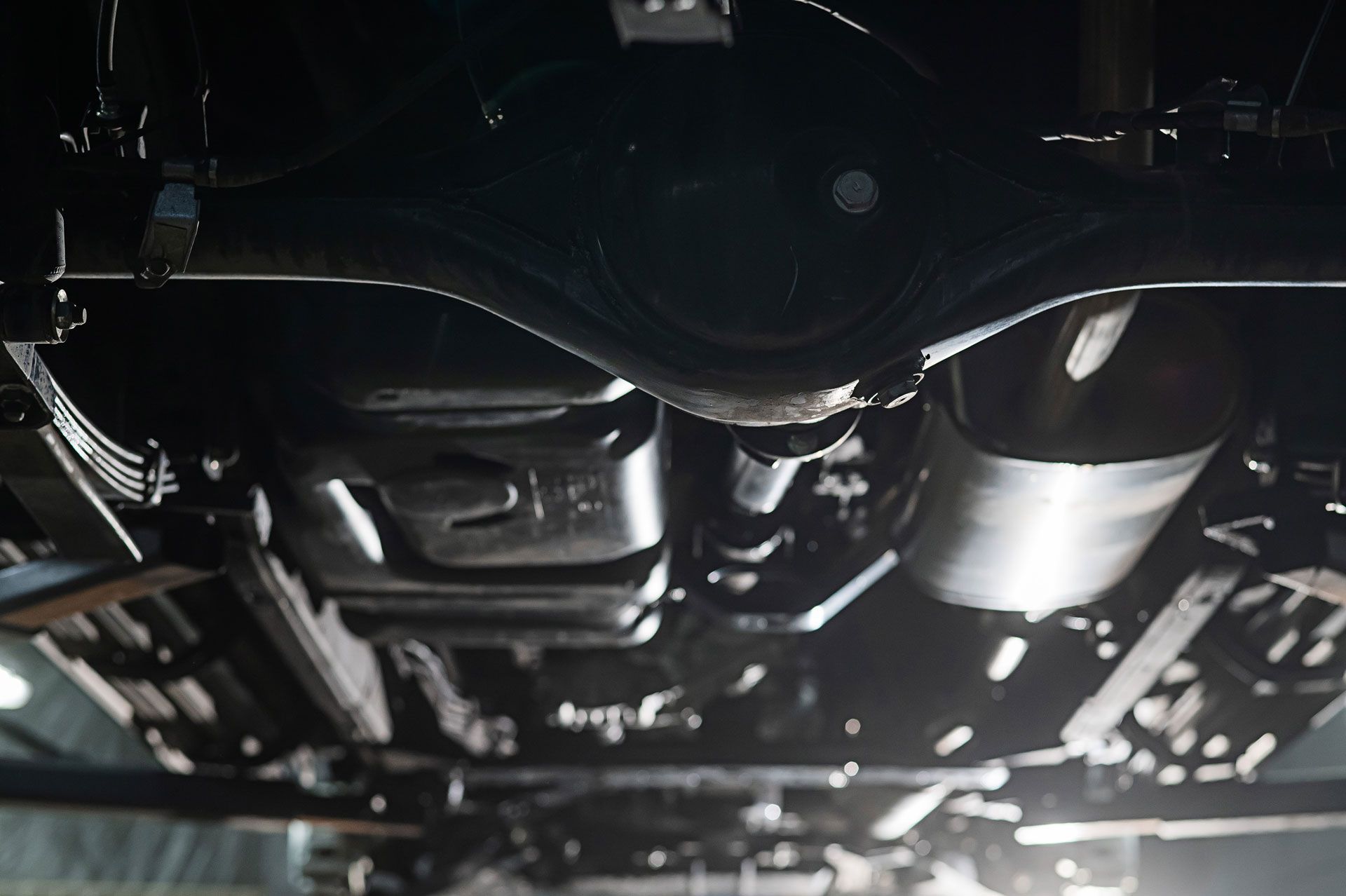 Underside view of a vehicle, showing exhaust system, fuel tank, and suspension components.