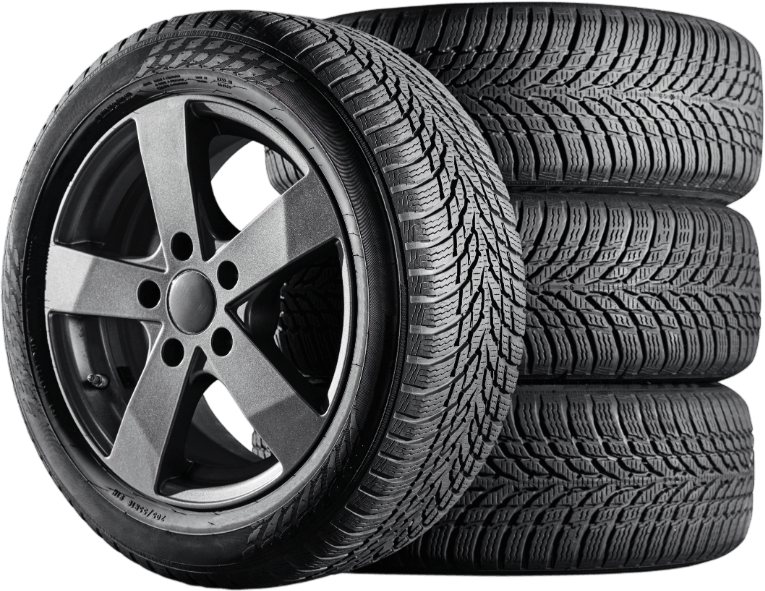 Four winter tires stacked on each other; one mounted on a gray alloy wheel.
