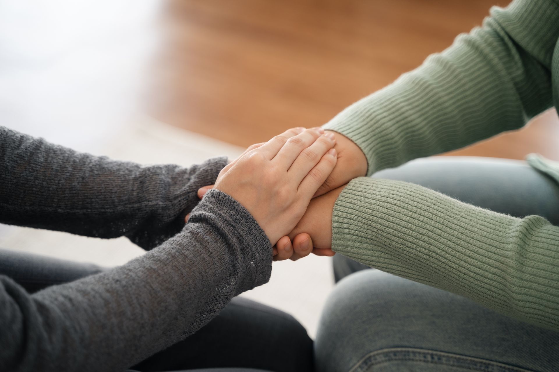 Two people holding hands, offering comfort and support.