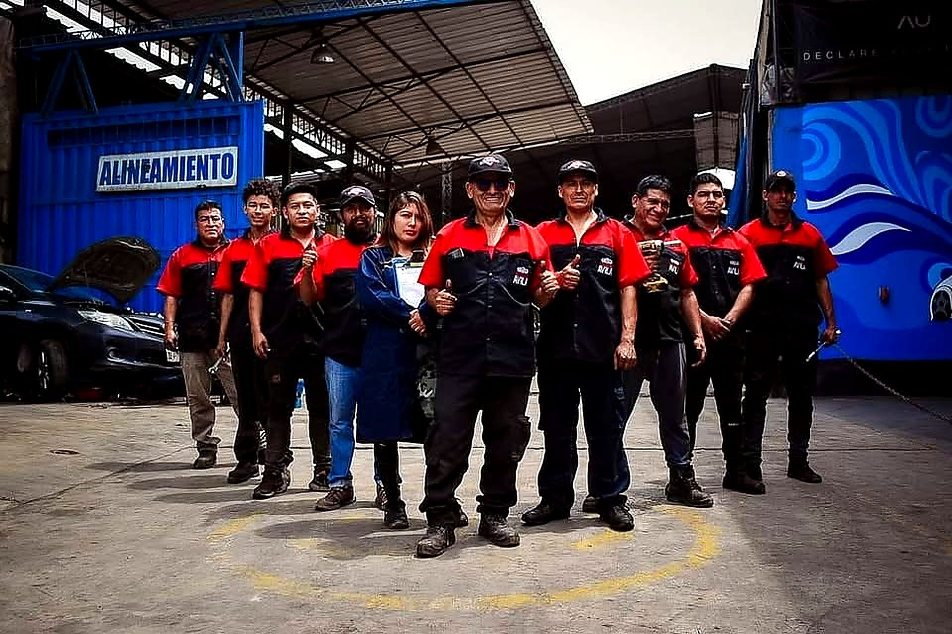 Un grupo de diez trabajadores con uniformes idénticos de color negro y rojo