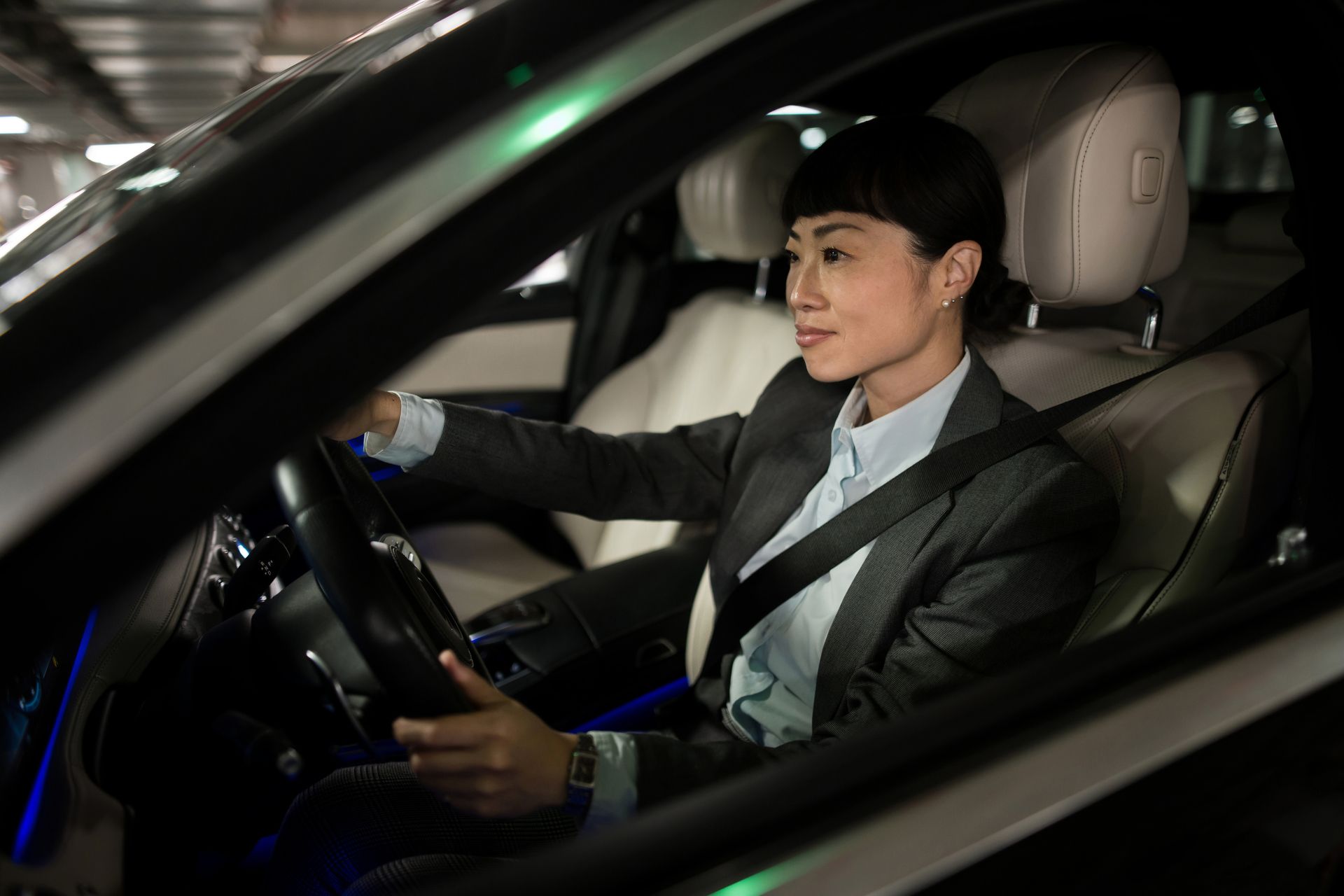A woman in a suit and tie is driving a car.